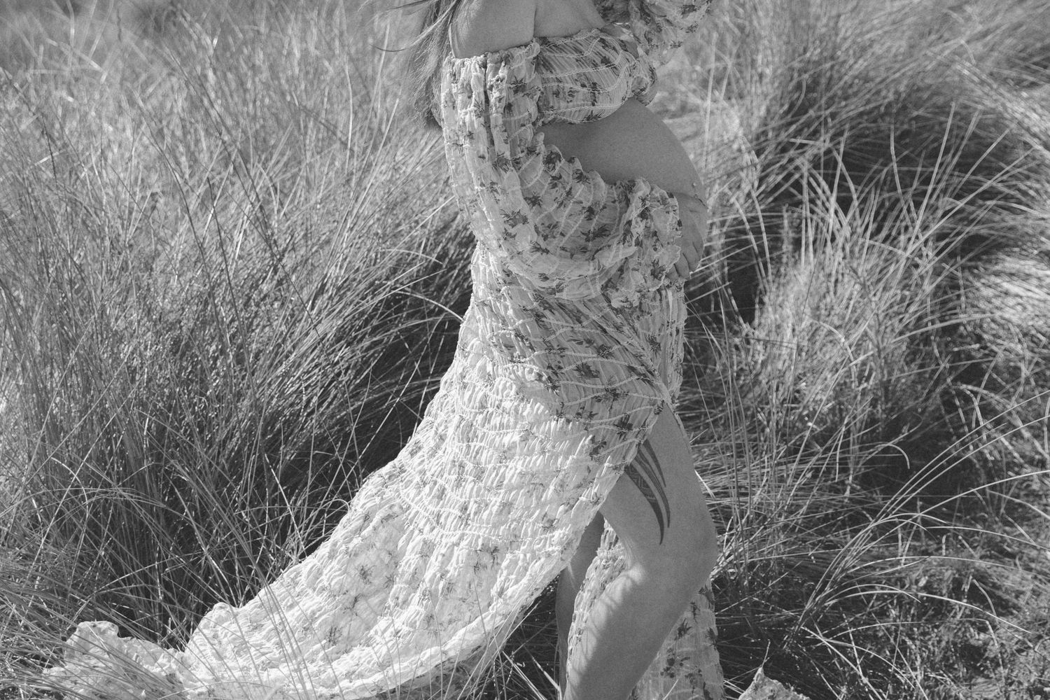 Intimate maternity portraits captured in a serene field of tall grass under moody skies.