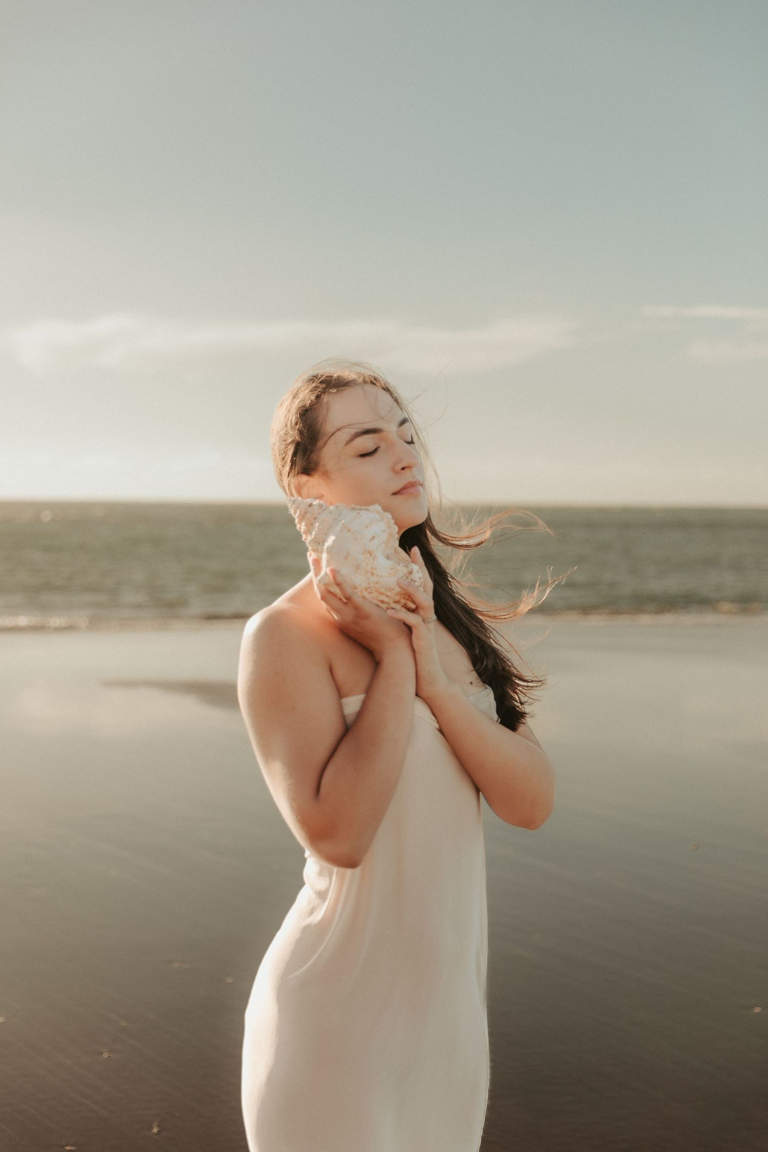 Seaside portrait with soft muted tones against a calm ocean backdrop.