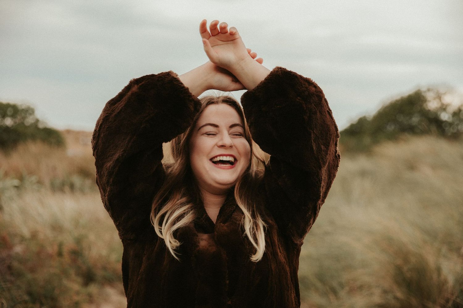 Joyful expressions captured in warm evening light among natural grasslands.