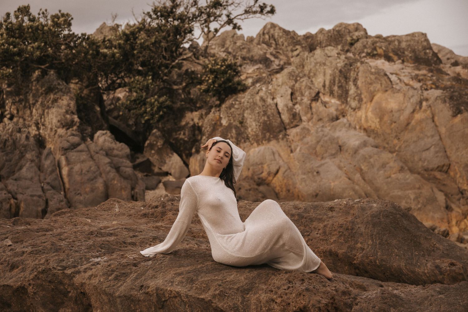 A dreamy outdoor maternity photoshoot in a rocky desert landscape at golden hour.