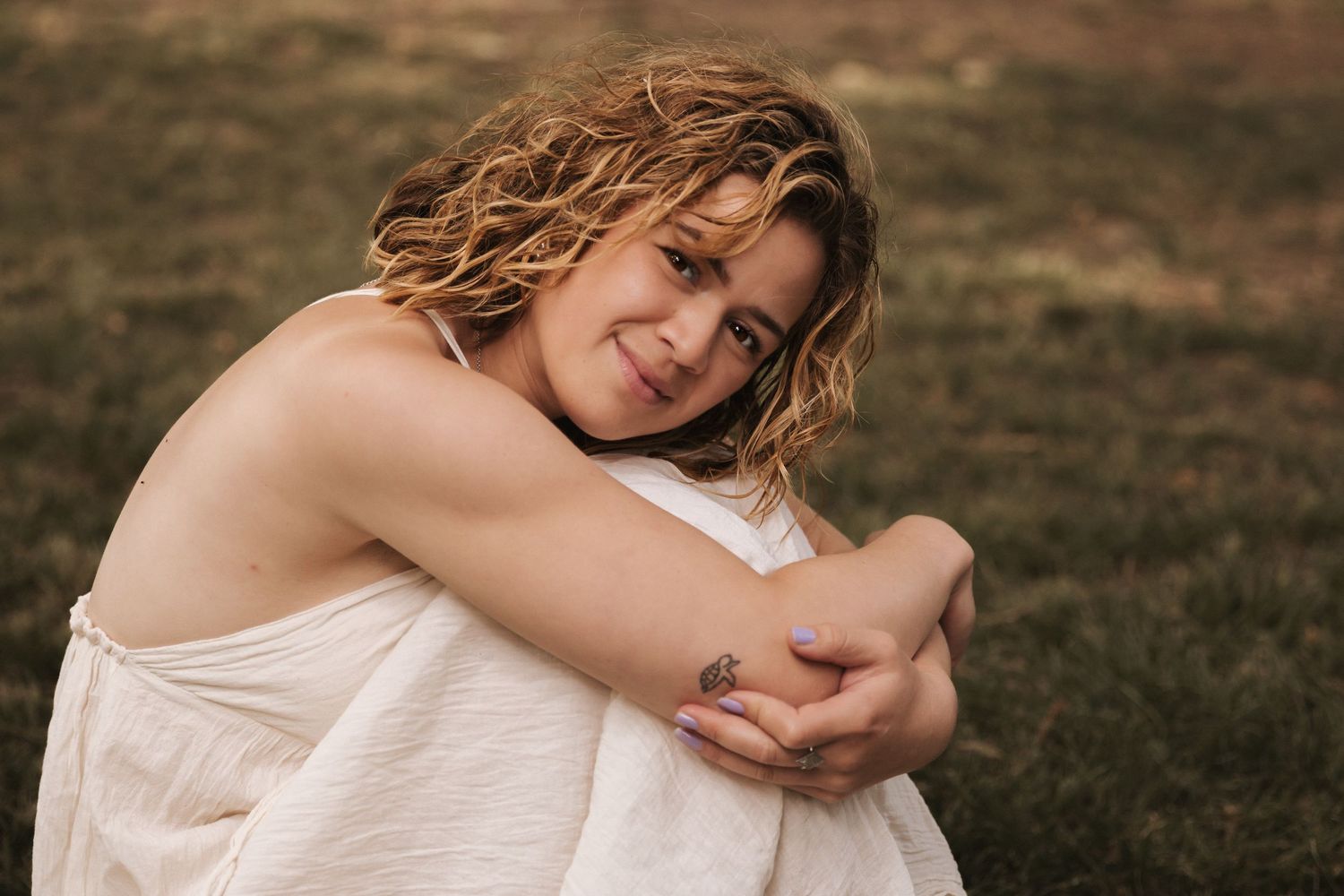Artistic outdoor portrait in white outfit against natural woodland setting during golden hour.