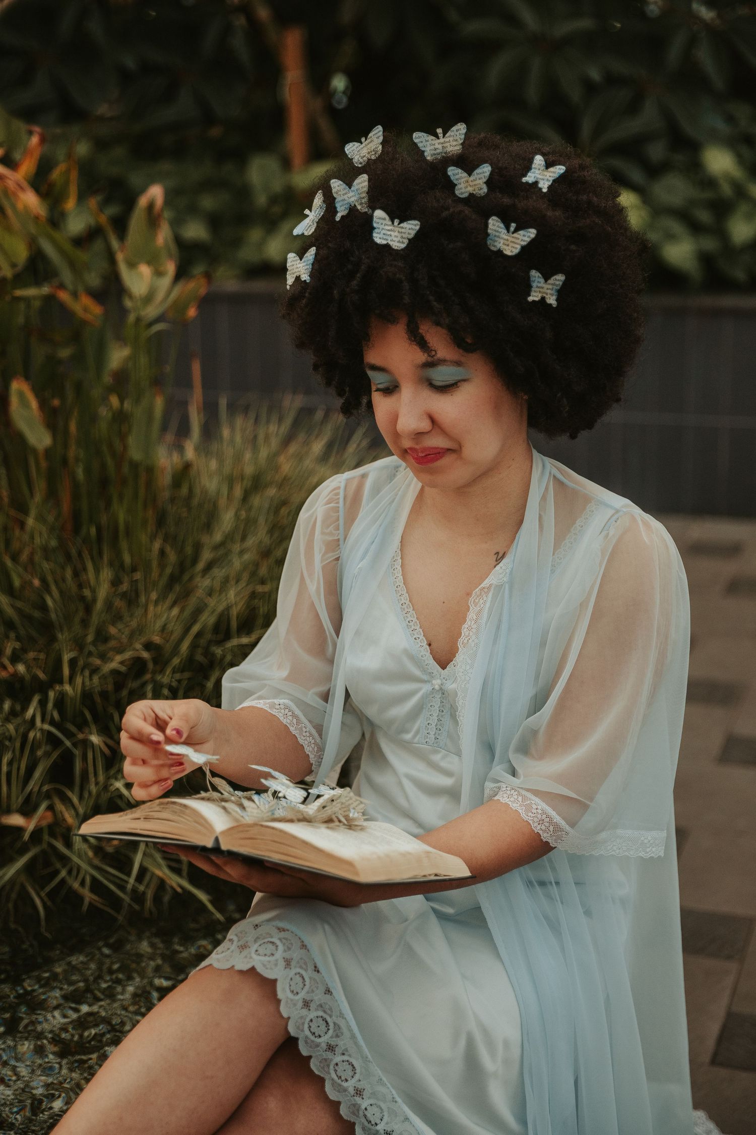 Ethereal portrait in white dress with decorative butterflies and book.