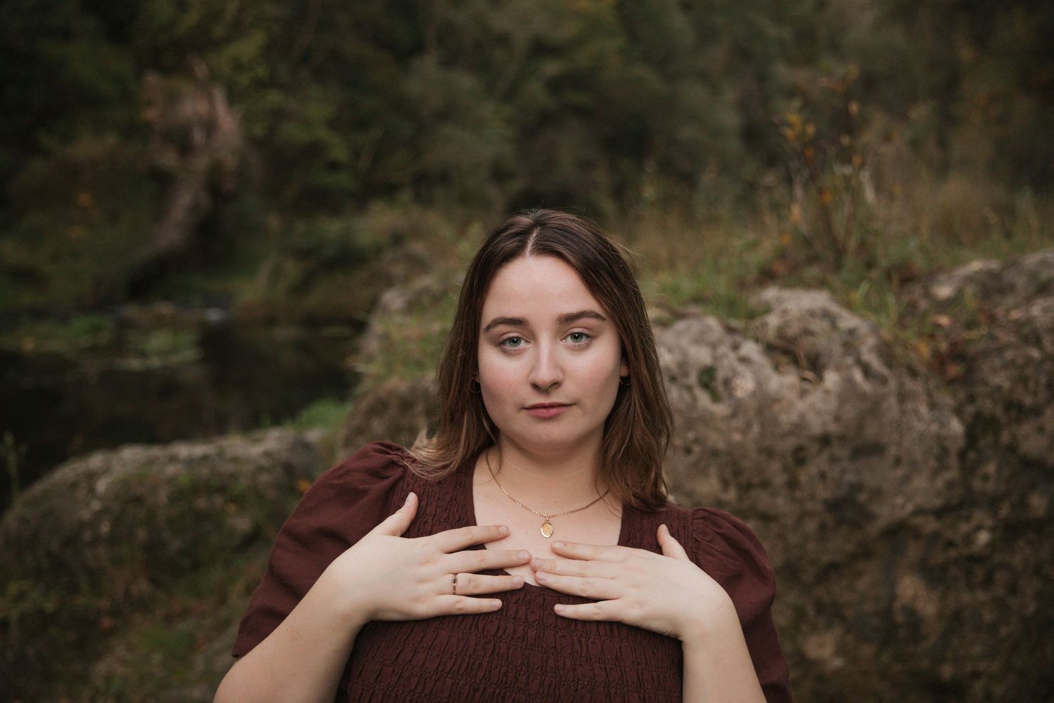 An intimate portrait in burgundy against mossy rocks and forest scenery.