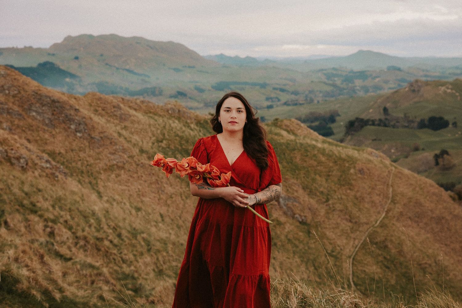 Scenic mountain landscape with figure in flowing red dress against rolling hills.
