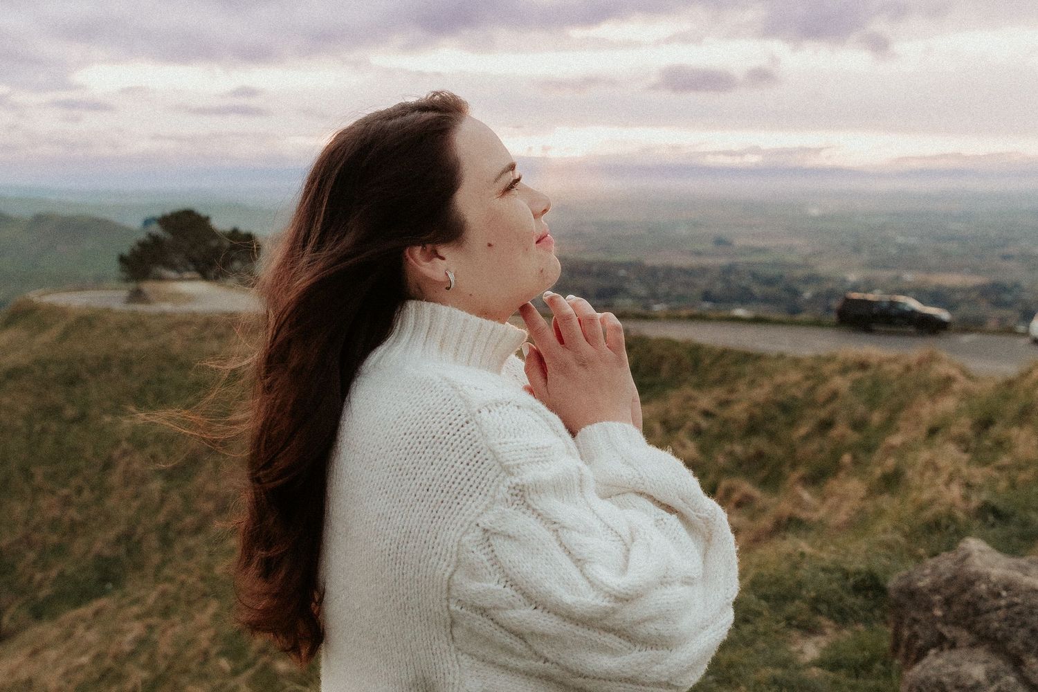Ethereal portraits captured against cloudy skies and rolling hills in soft lighting.
