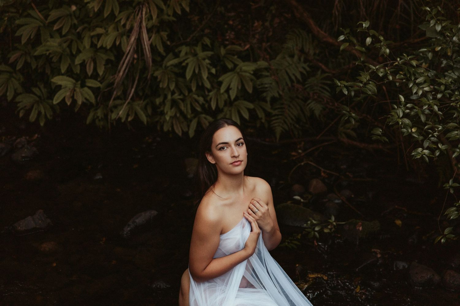 Moody forest photoshoot with natural greenery and dark shadows.