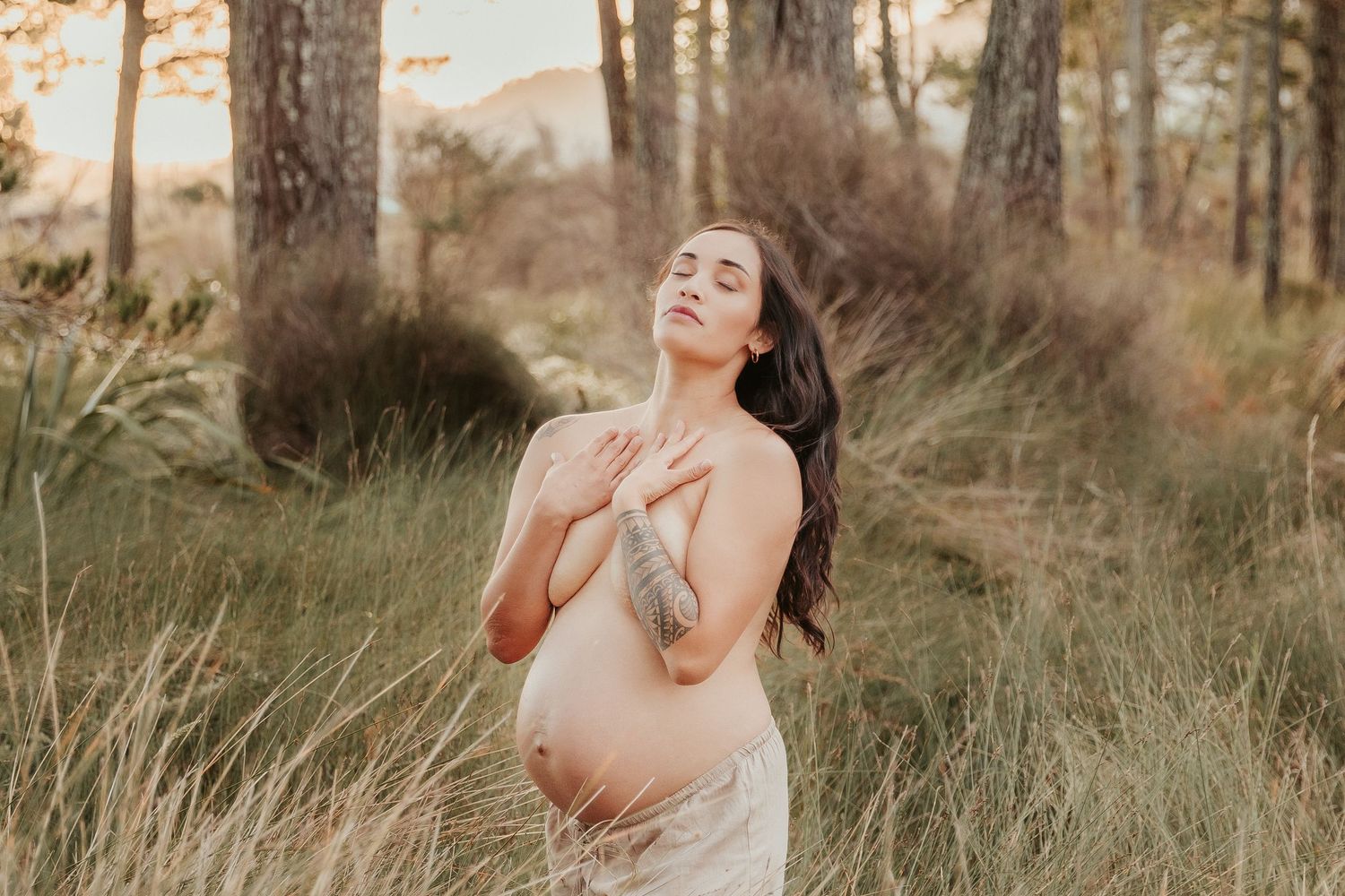 Natural light portrait among tall grass and pine trees at golden hour.