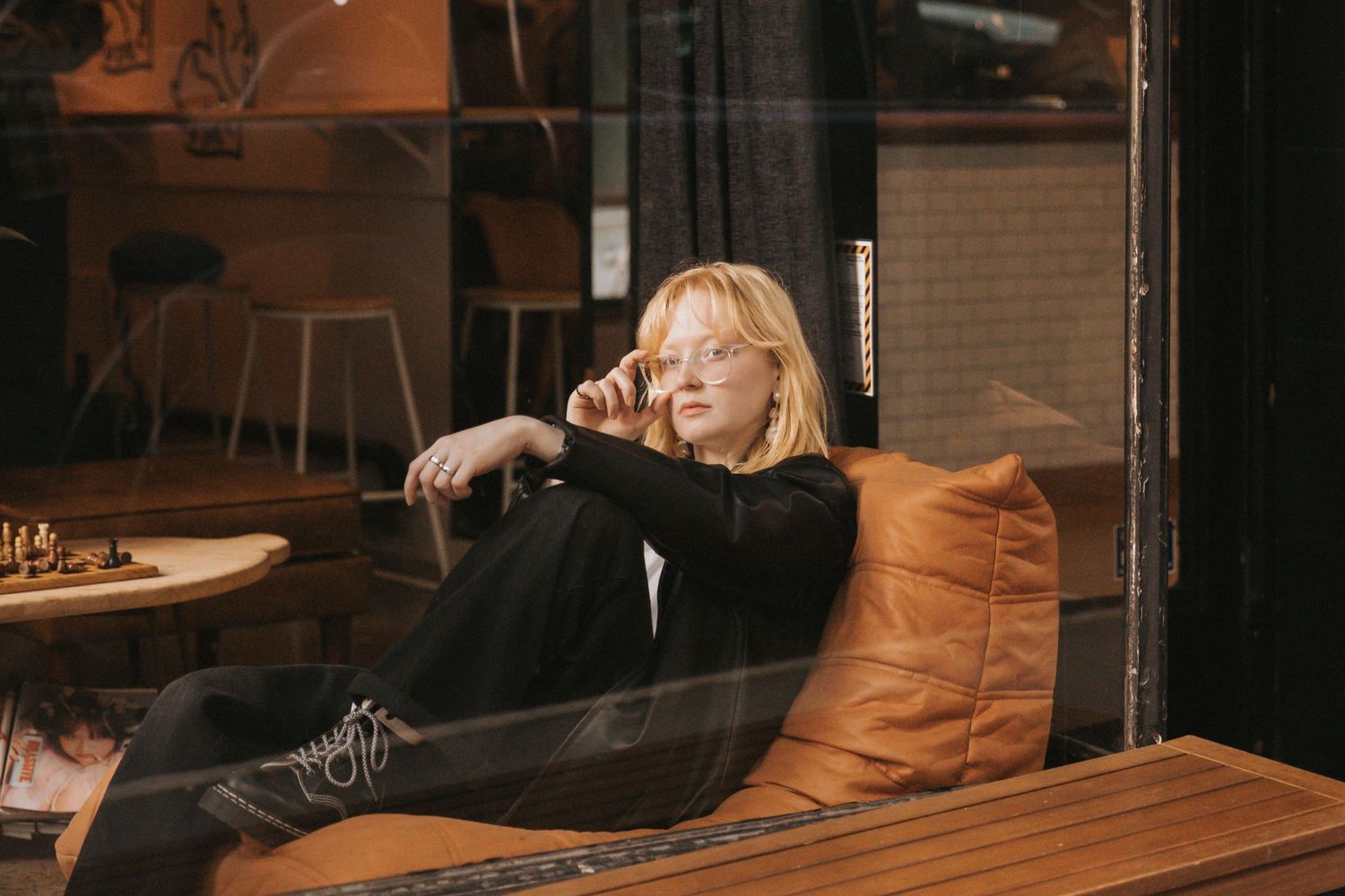 A person sits at a wooden table in a dimly lit restaurant interior with industrial-style decor.