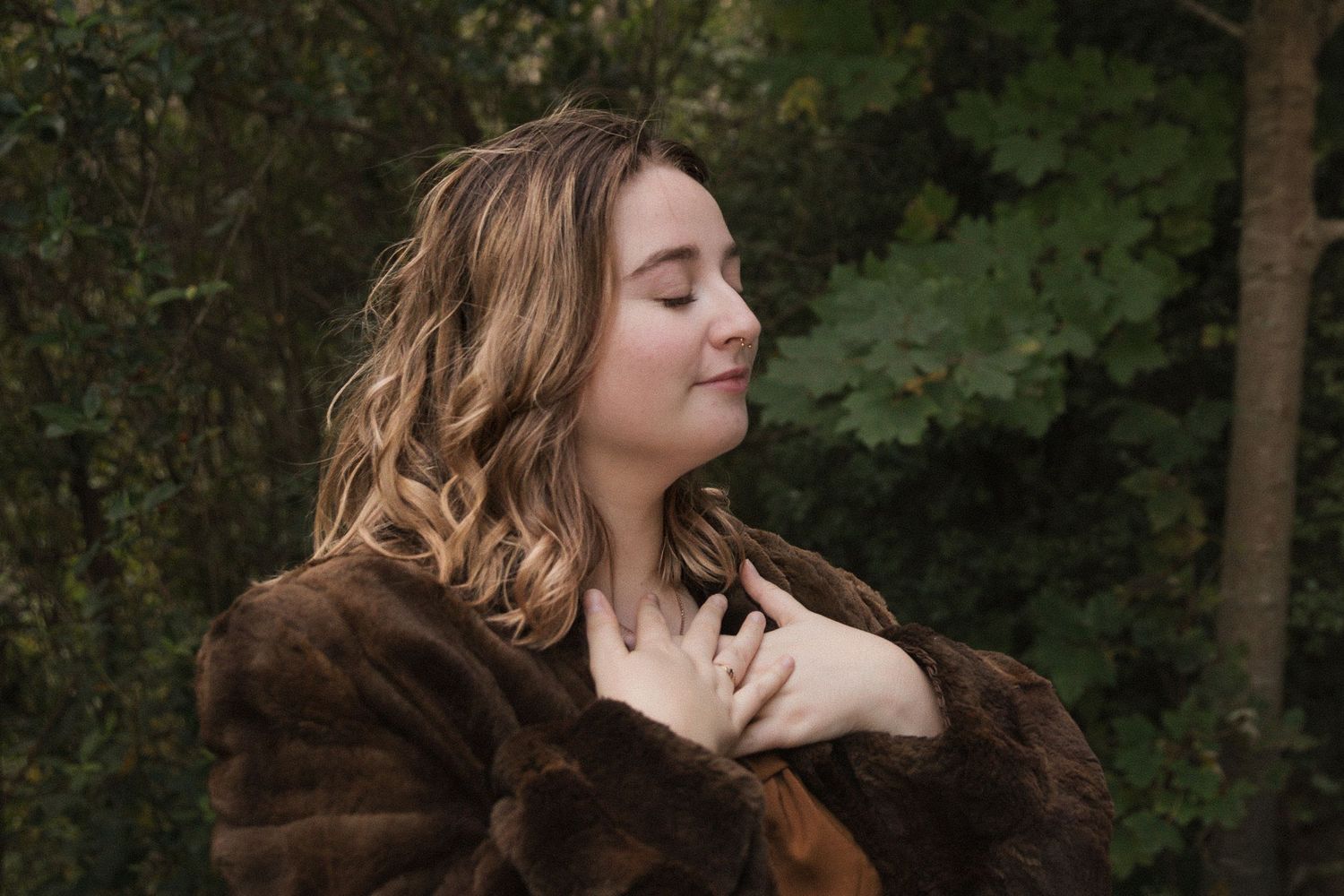 Ethereal autumn photoshoot featuring brown fur coat and natural woodland backdrop.