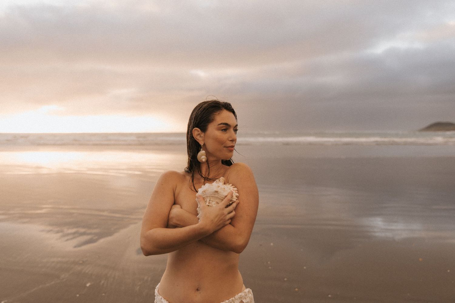 Ethereal beach photoshoot with waves crashing and cloudy skies at dusk.