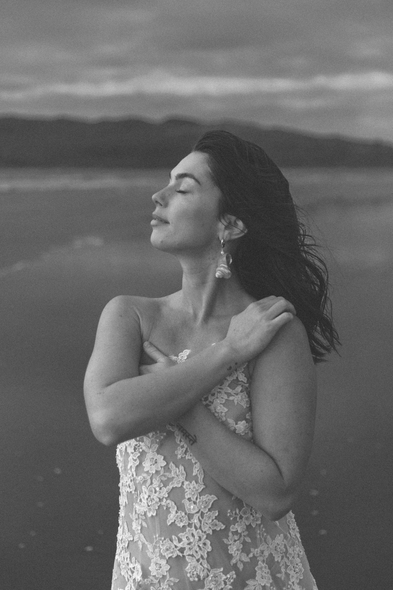 Dramatic black and white portrait showcasing elegant lace details against moody skies.