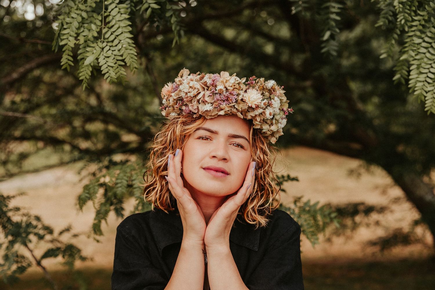 A whimsical outdoor portrait featuring a floral crown and natural lighting.
