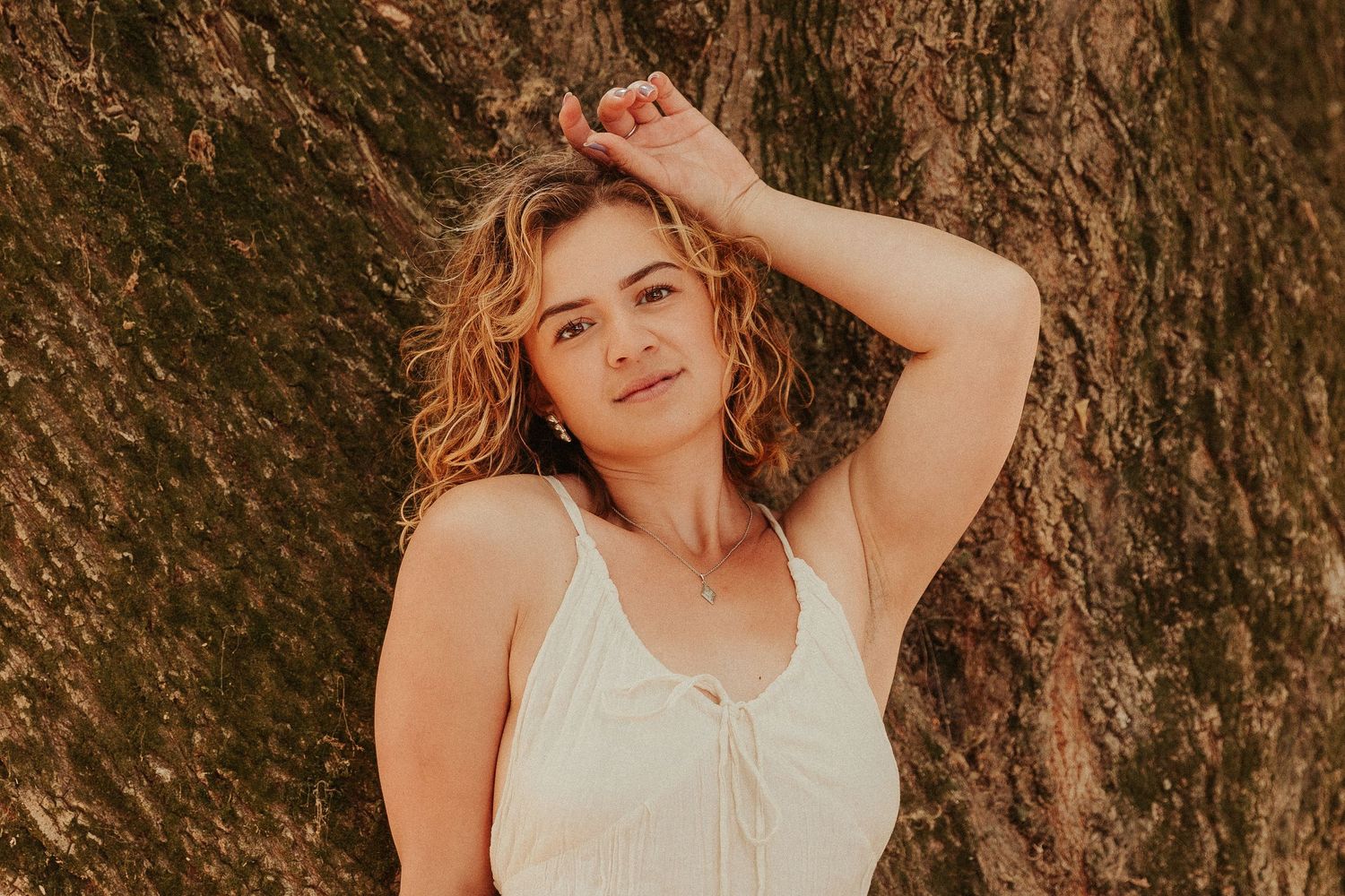 Portrait against textured rock wall with natural summer lighting.