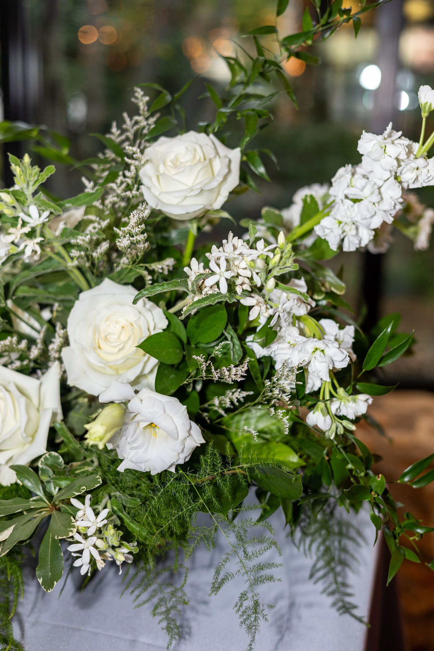 White roses and delicate floral arrangements with greenery in an elegant wedding centerpiece.