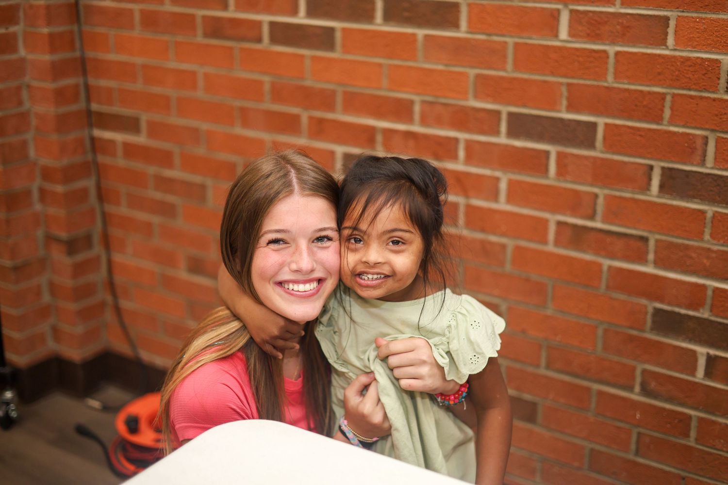 Joyful moment captured between caregiver and child against brick wall background.