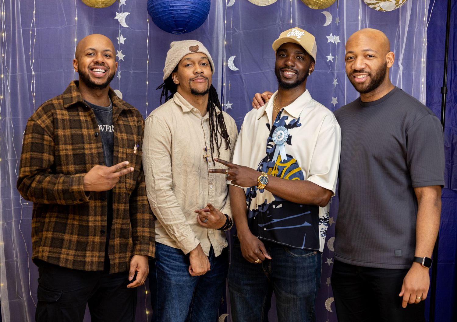 A group of people gather together at a party with blue decorations and lighting in the background.