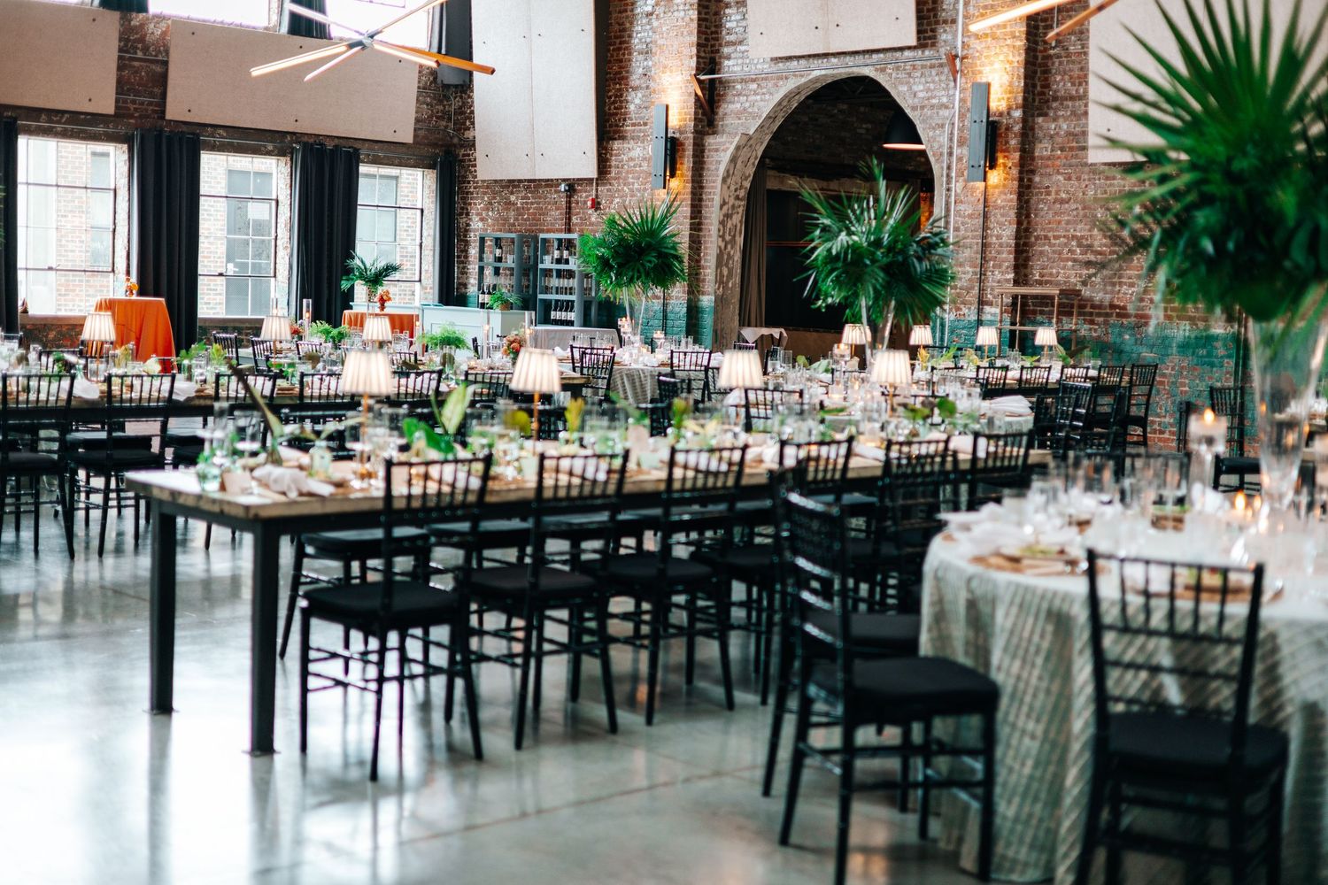 A rustic industrial wedding venue with exposed brick walls, long tables, and elegant place settings in a spacious hall.
