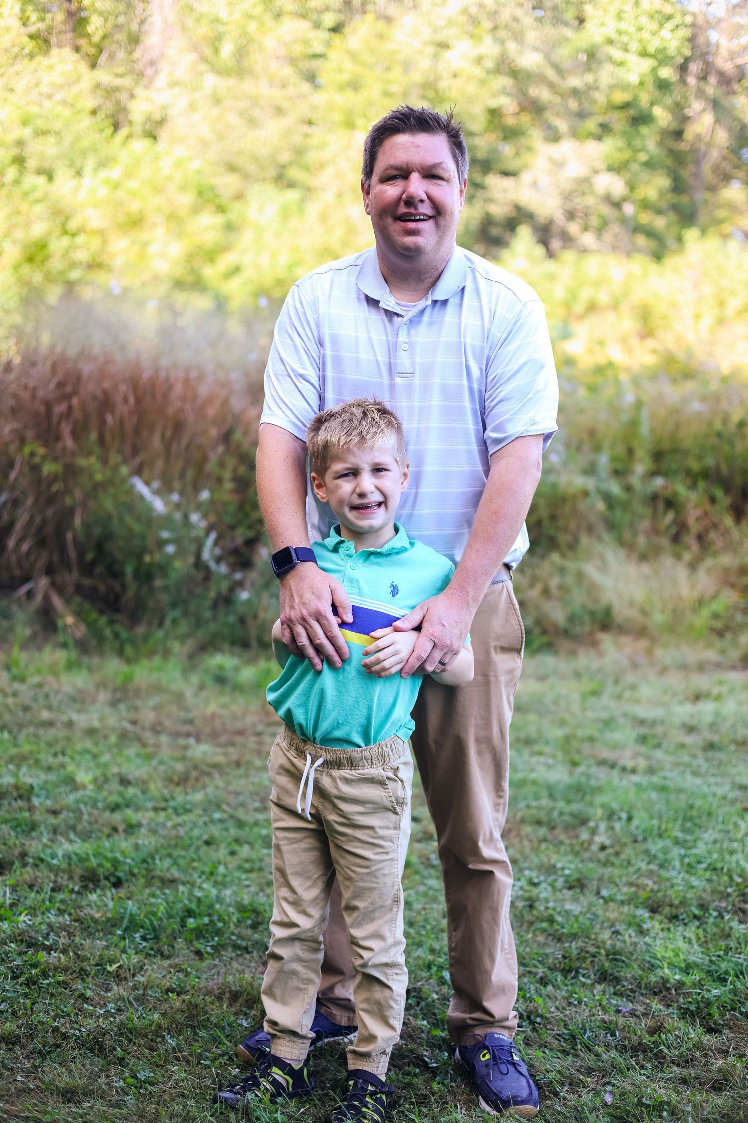 A playful outdoor photo session in a grassy field showing joyful expressions and casual attire.
