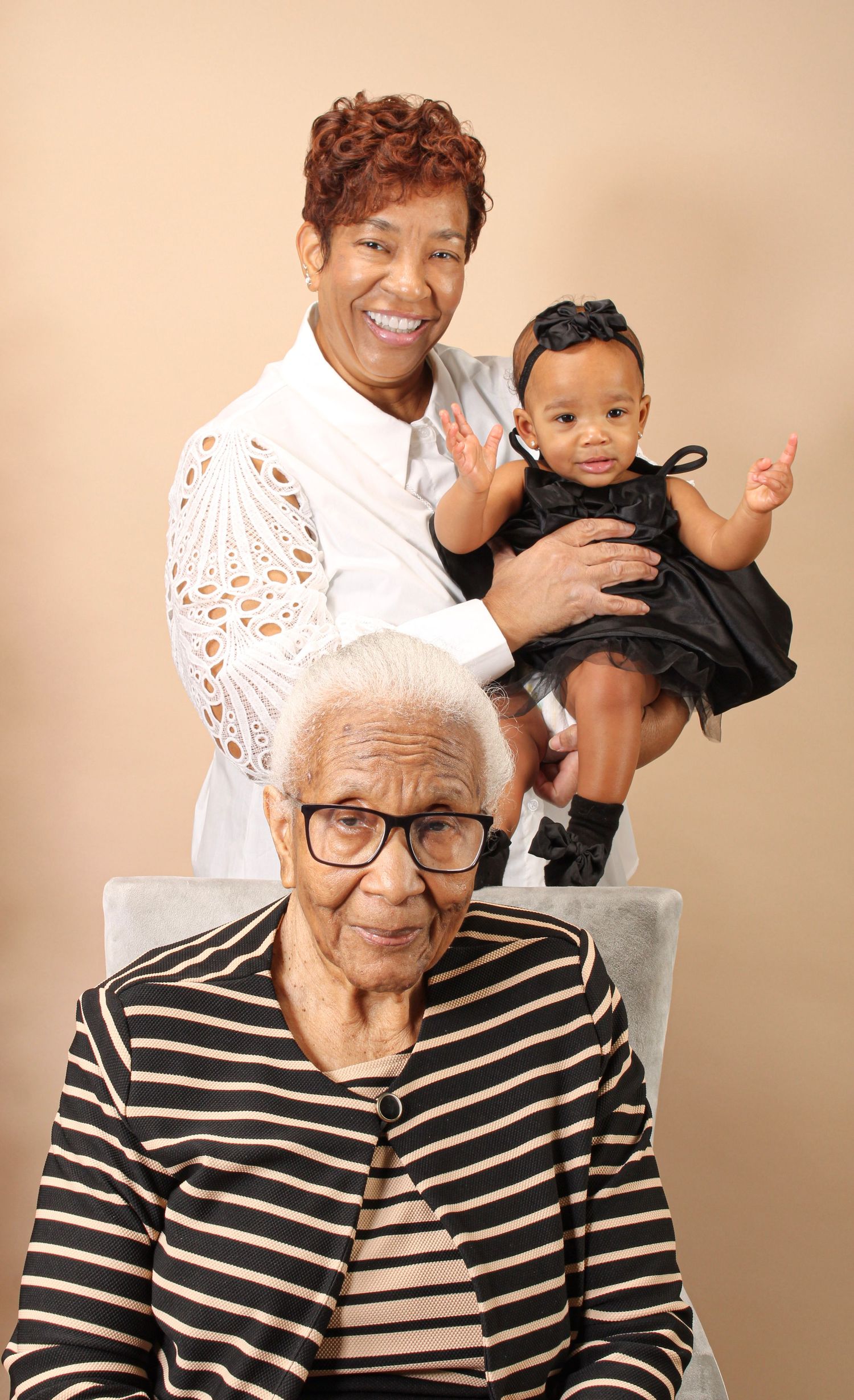 Multi-generational family portrait with someone wearing a striped shirt against a beige background.