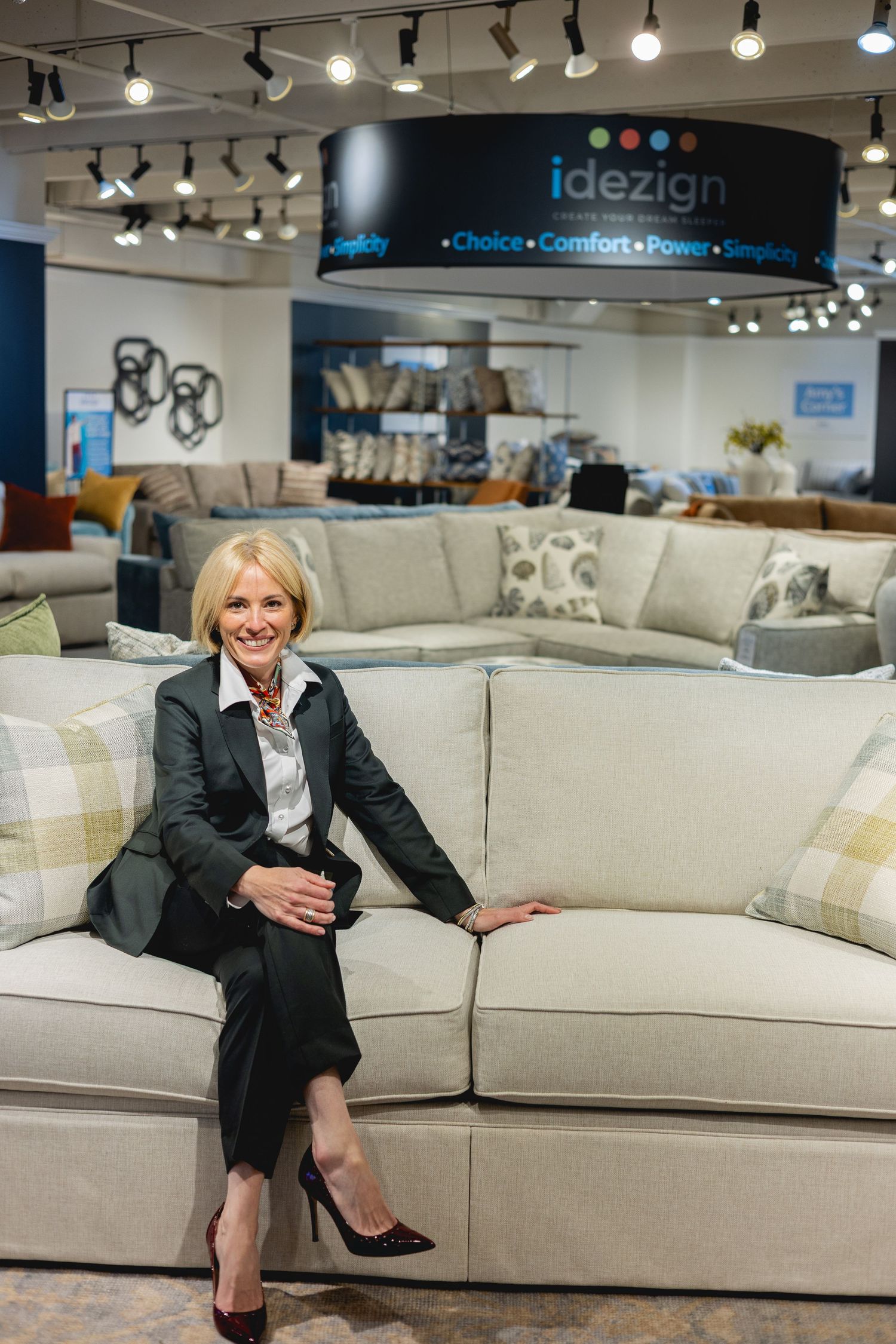 Modern furniture showroom displays a white sectional sofa under track lighting with a professional business setting.