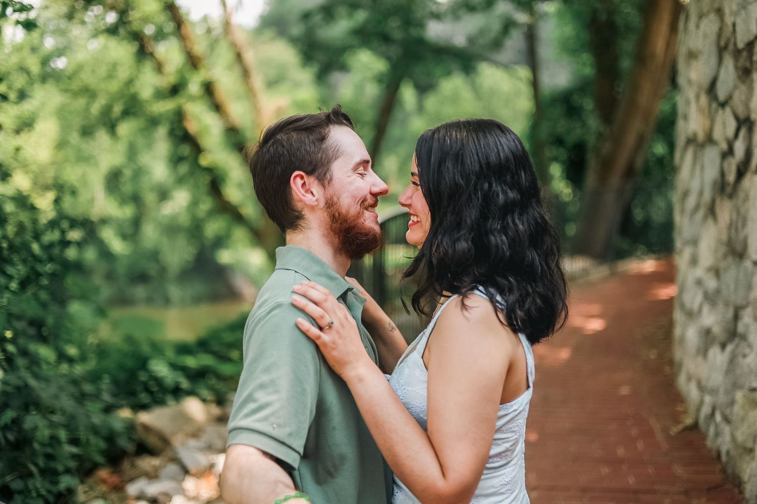 A couple shares a joyful moment together on a tree-lined path in a lush garden setting.