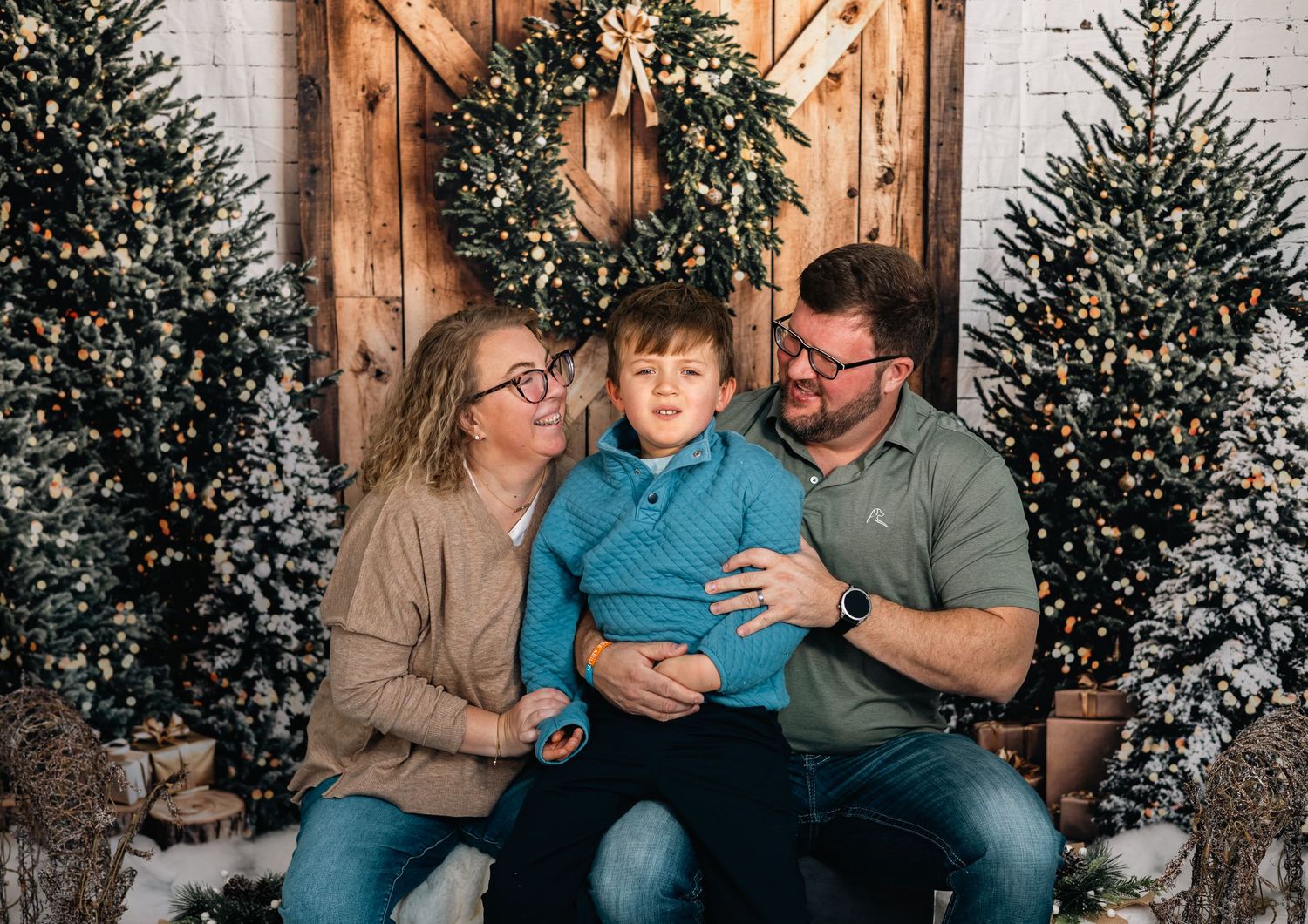 Family shares joyful moments together on a couch during holiday season with decorated Christmas trees in background.