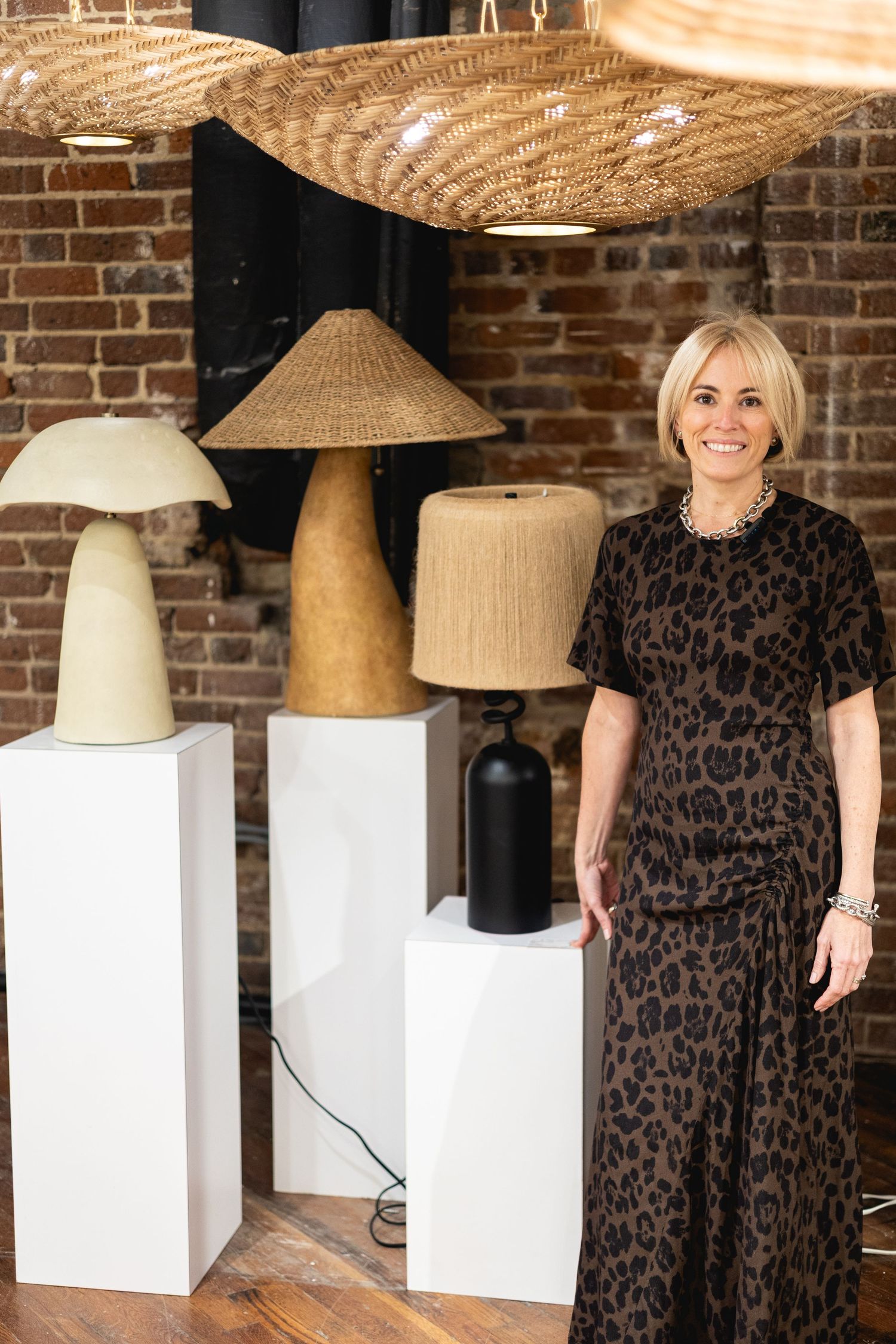 Stylish display of modern woven lamp shades on white pedestals against exposed brick wall in home decor setting.