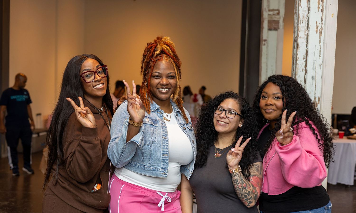 A group of people enjoying themselves at a social gathering, with some making peace signs and smiling.