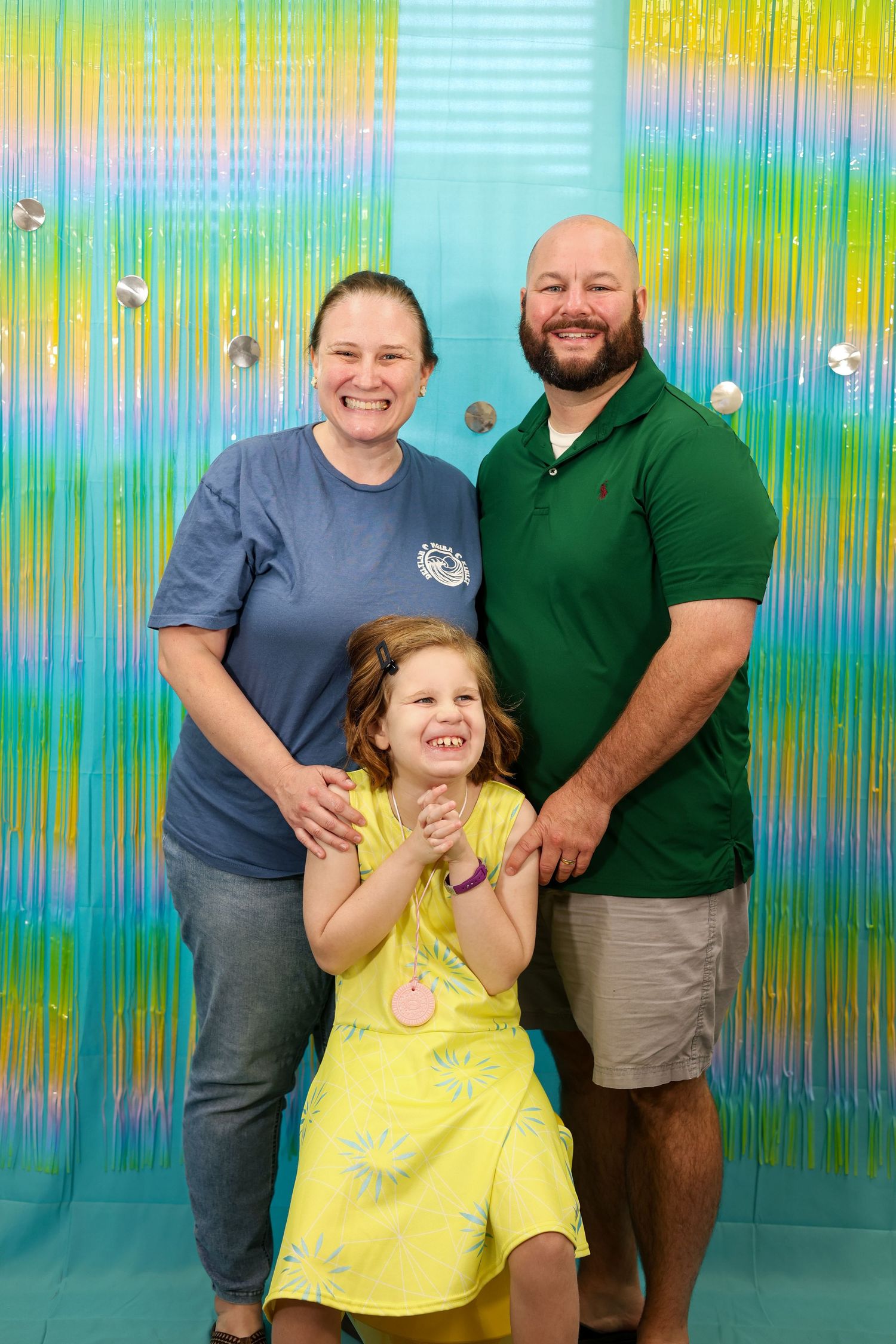 Happy group poses for photos against a colorful holographic backdrop.