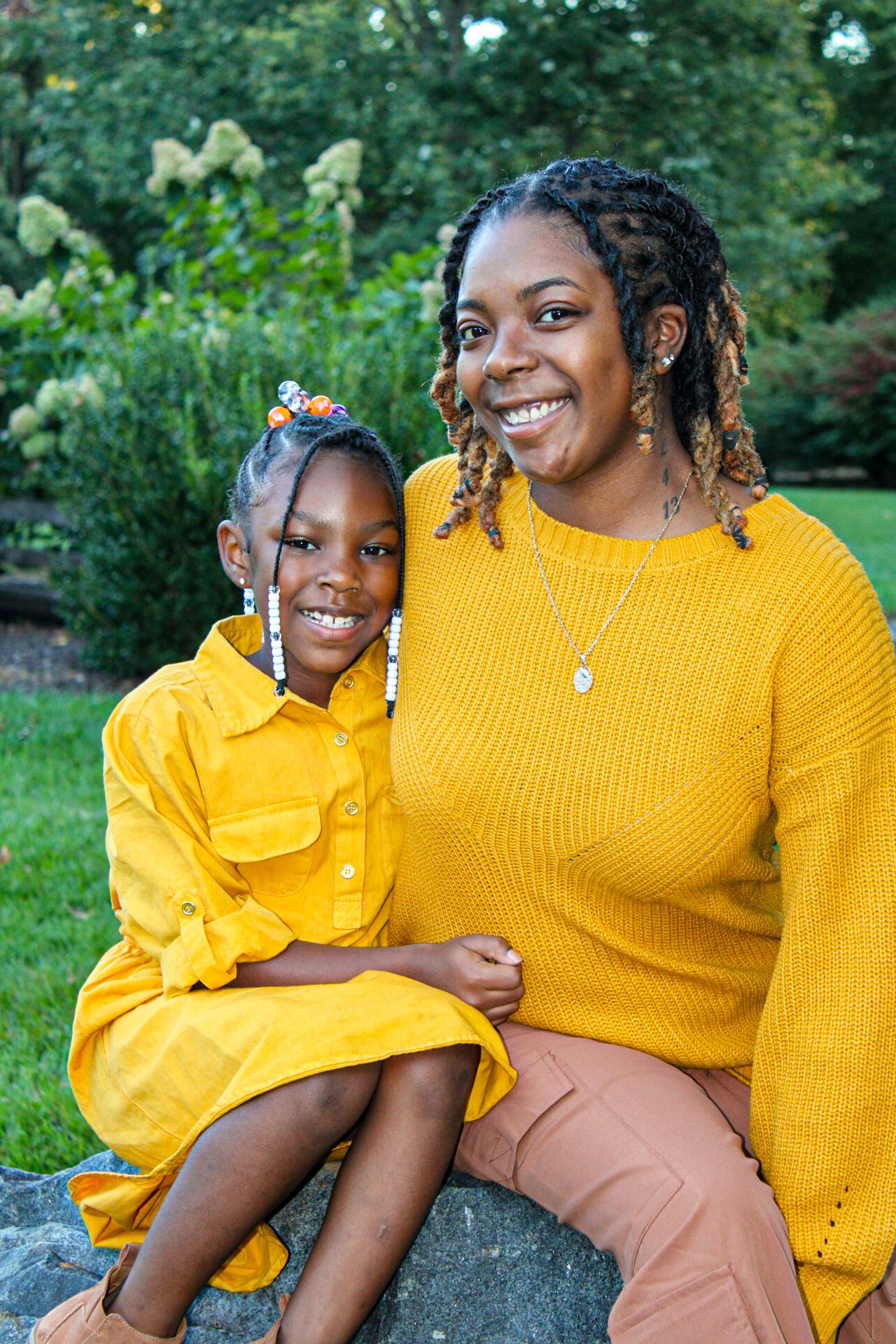 Playful outdoor photoshoot with matching yellow sweaters against a natural background.