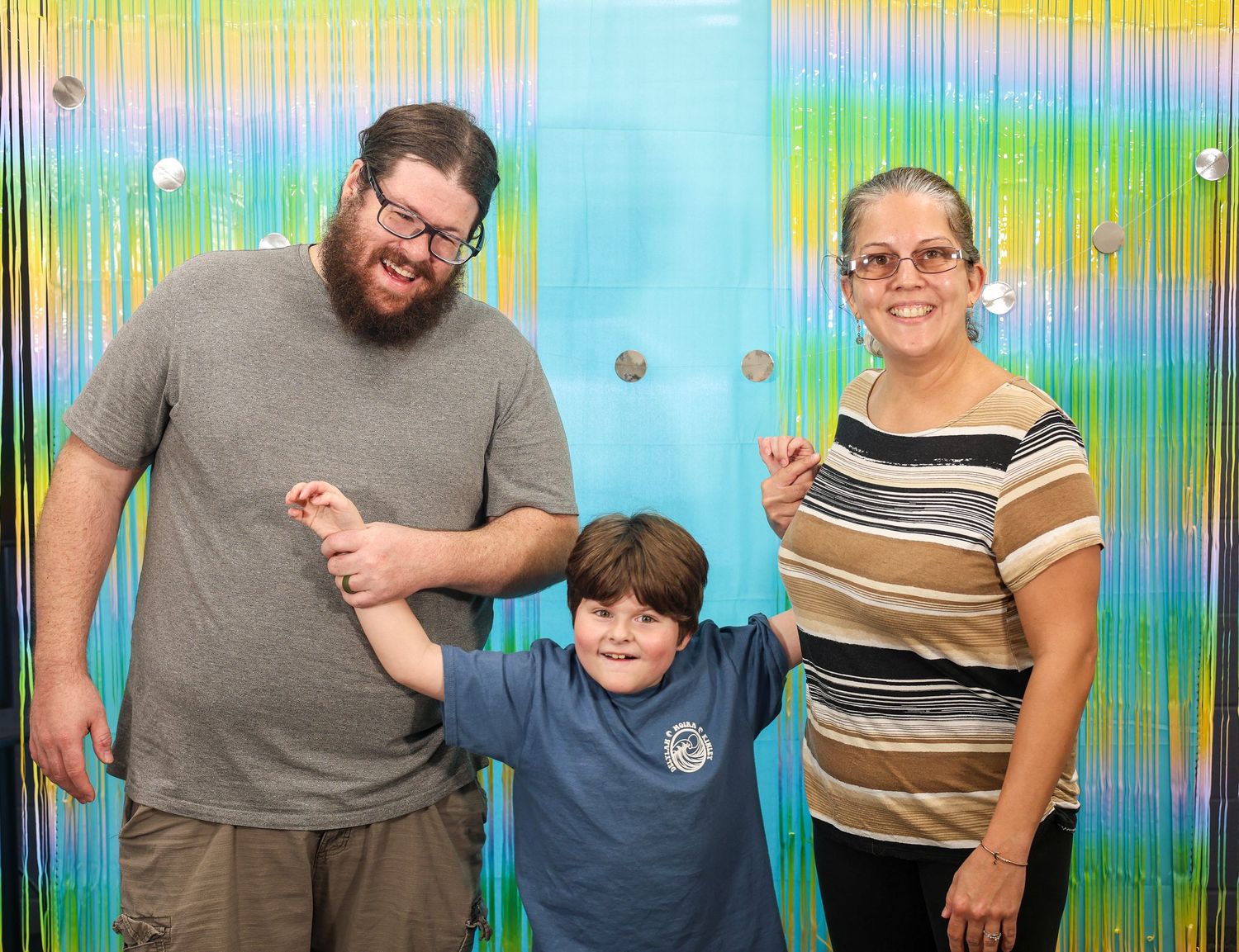 Family group photo against a bright streaked background with blue and green tones.