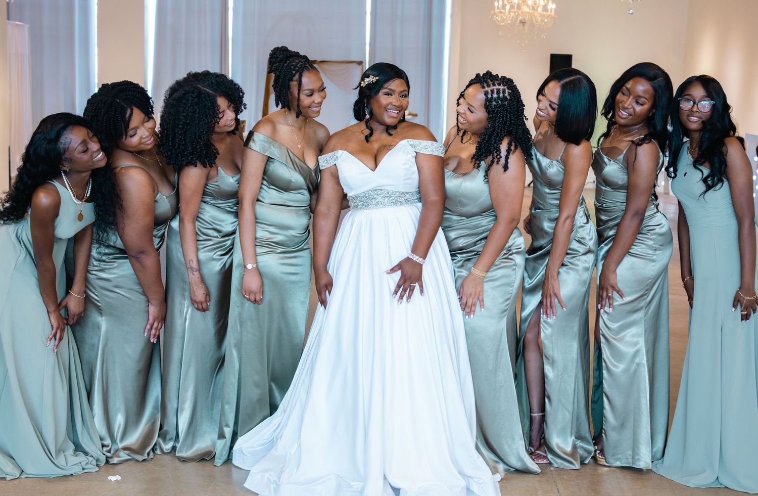 Wedding party in coordinated mint green bridesmaid dresses poses together in a line with the bride in white.