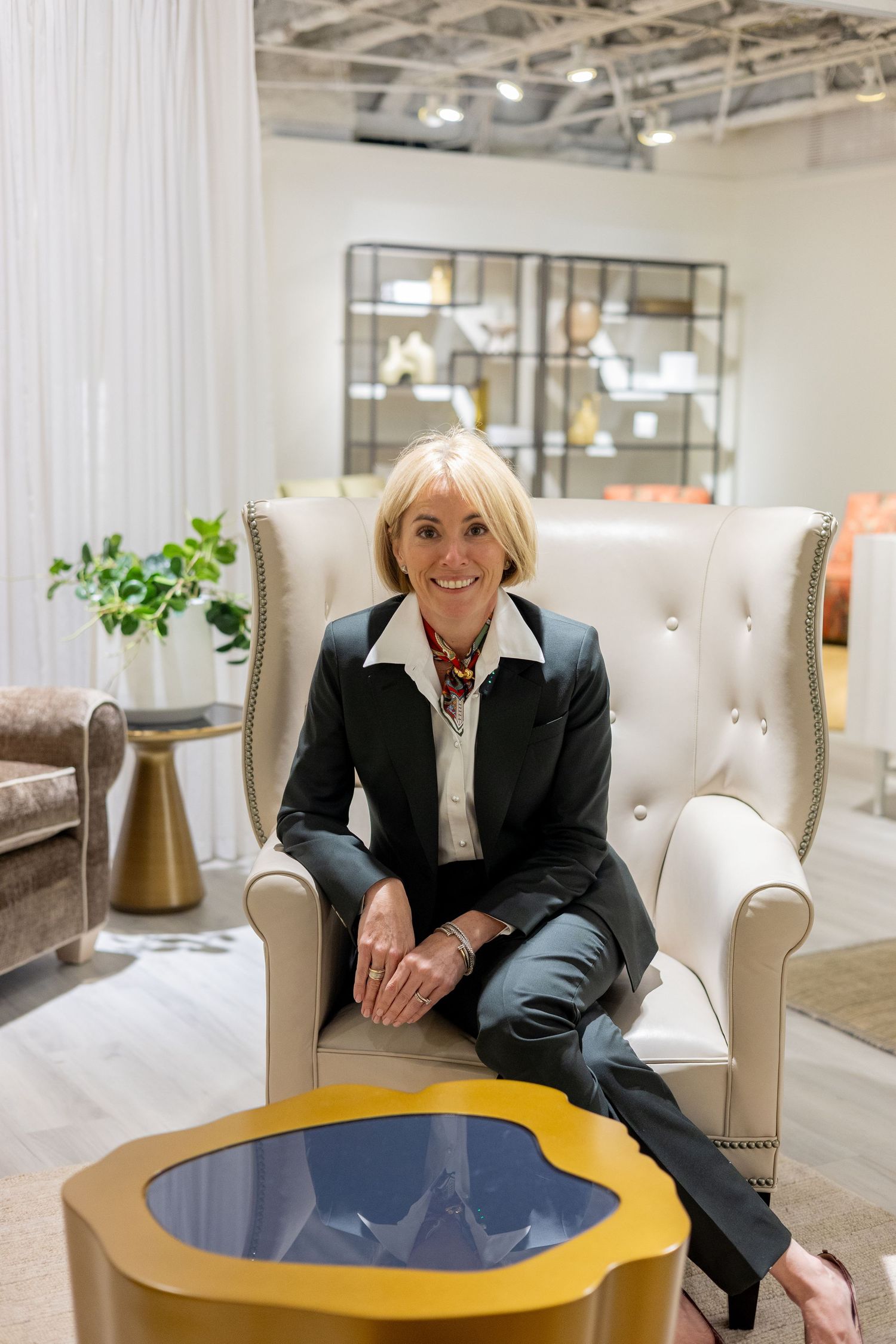A modern showroom interior featuring elegant cream-colored chairs and a round blue accent table.