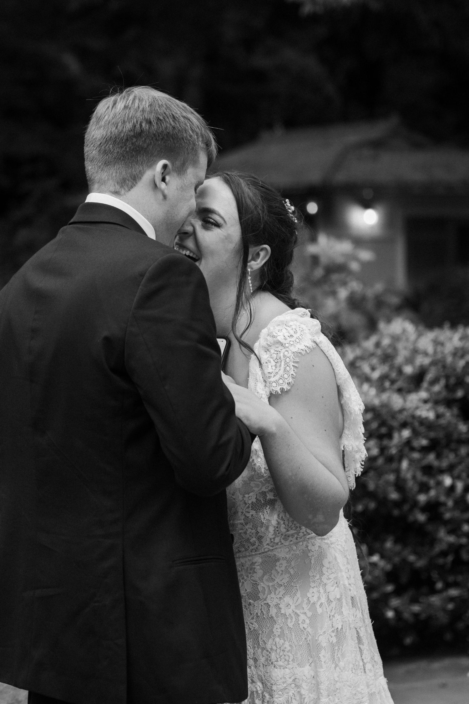 Black and white photo of a bride and groom sharing an intimate moment outdoors at their wedding ceremony.