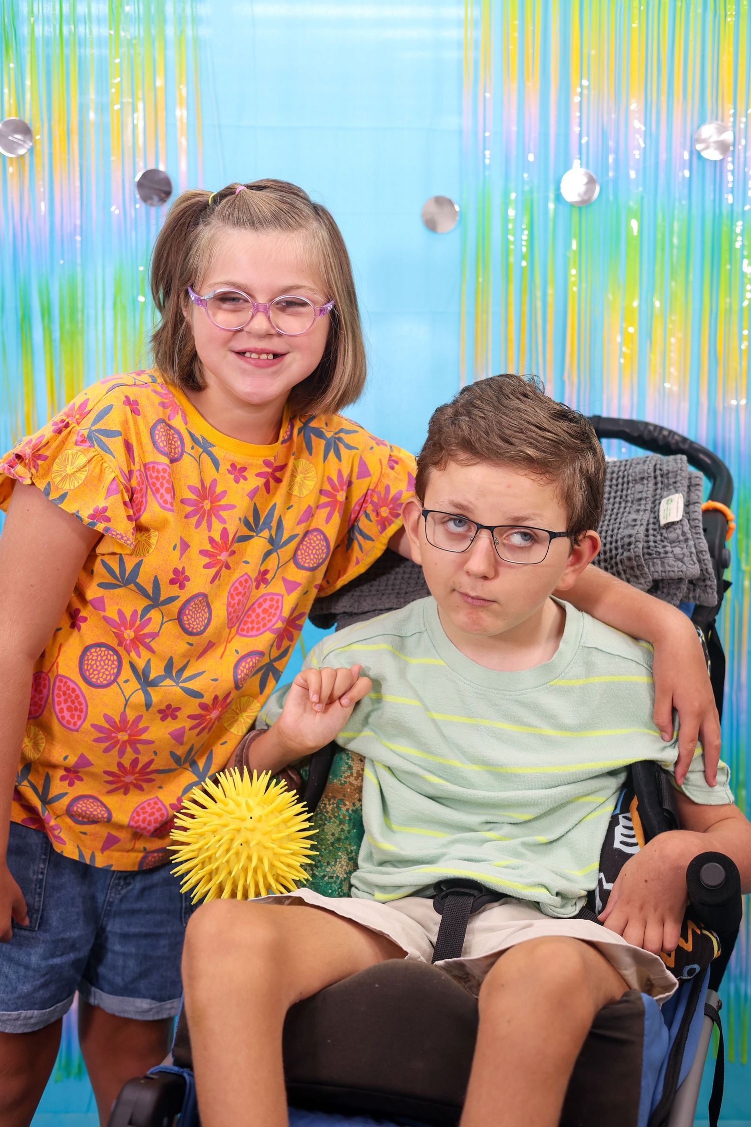 Group sitting together with a decorative sunburst on a vibrant blue and green background.