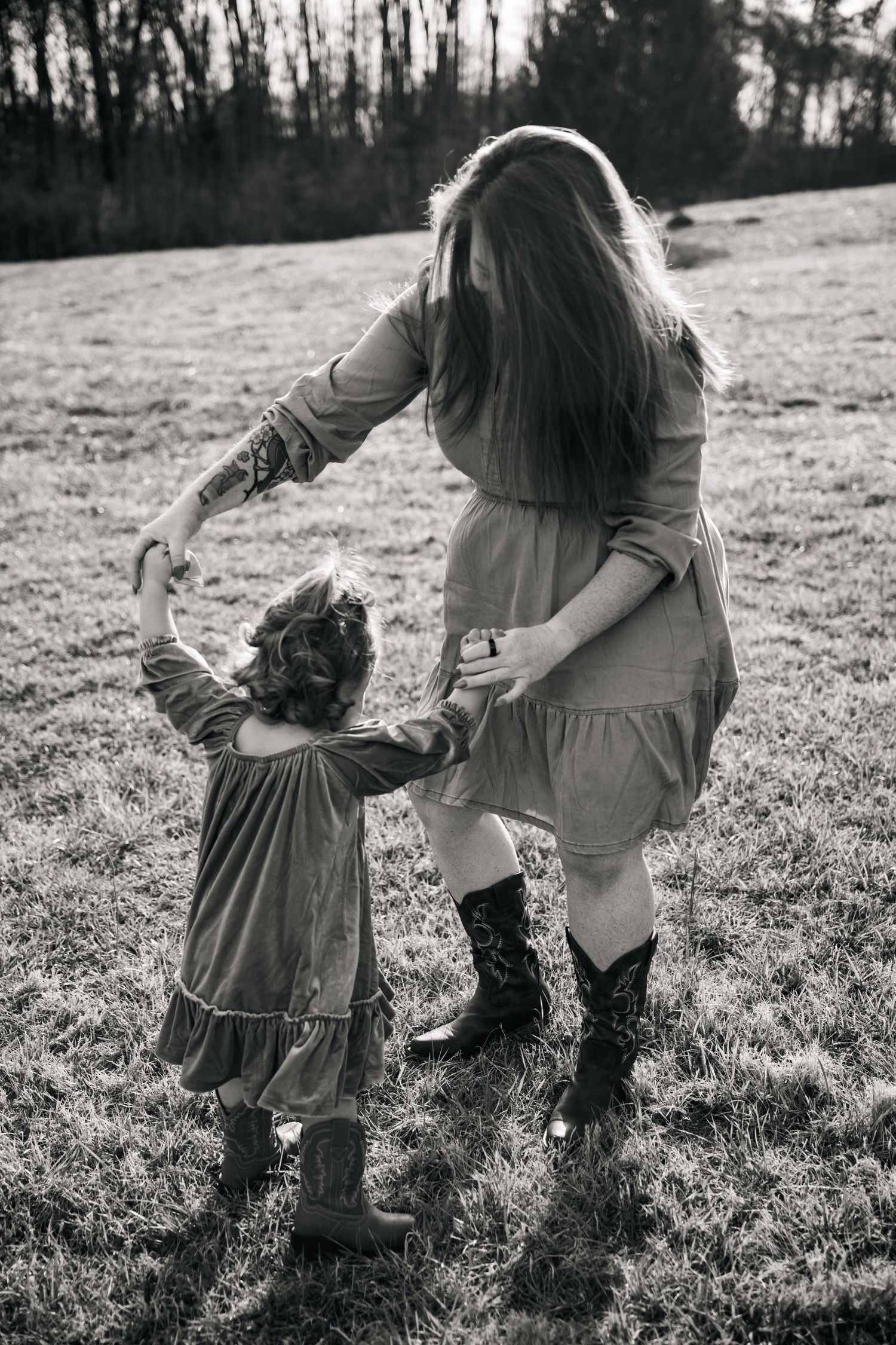Black and white photo series of parent and child walking hand in hand through a sunlit grassy field.