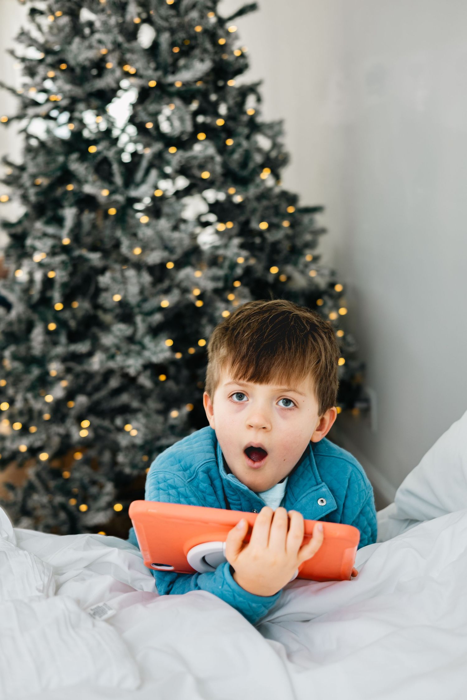 A series of holiday photos showing expressions of wonder and excitement against a decorated Christmas tree background.