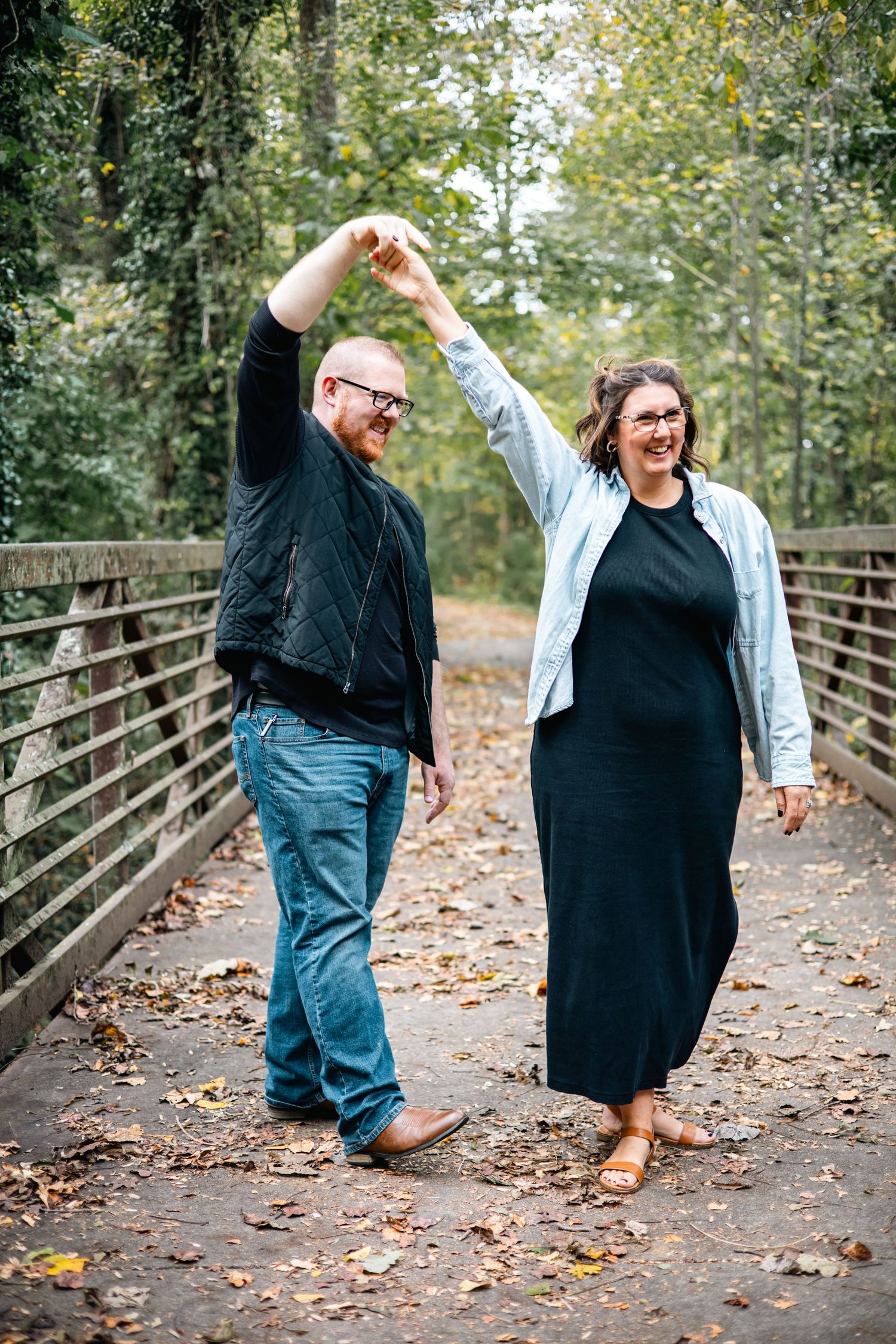 A playful sequence of dance moves on a wooden bridge covered in autumn leaves shows two people enjoying a fall day.