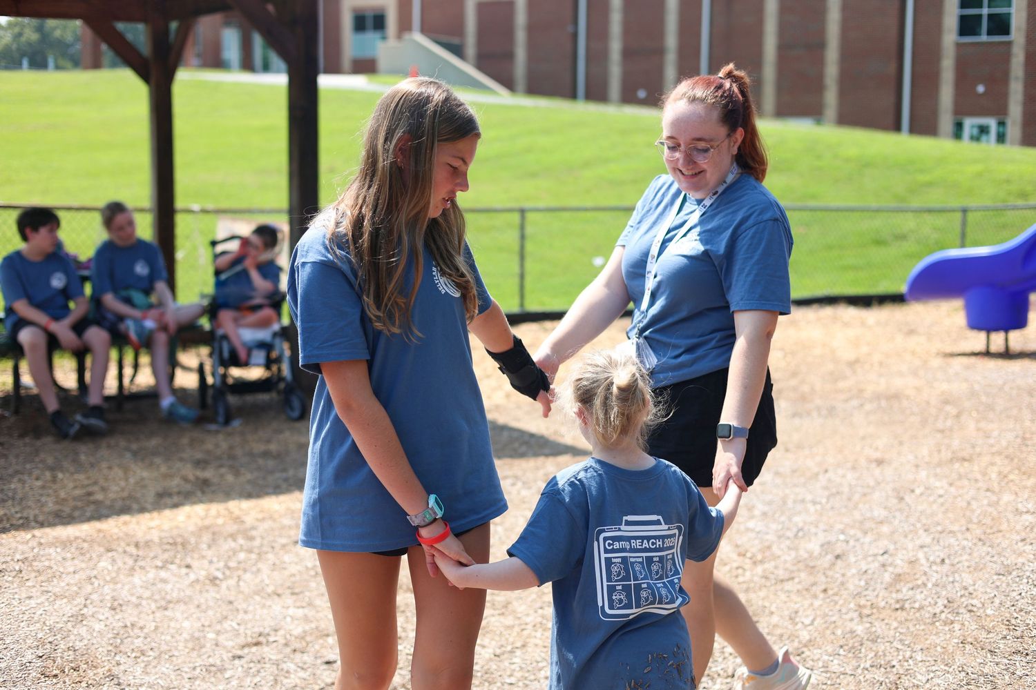 Students in matching blue uniforms interact during an outdoor activity on a playground.