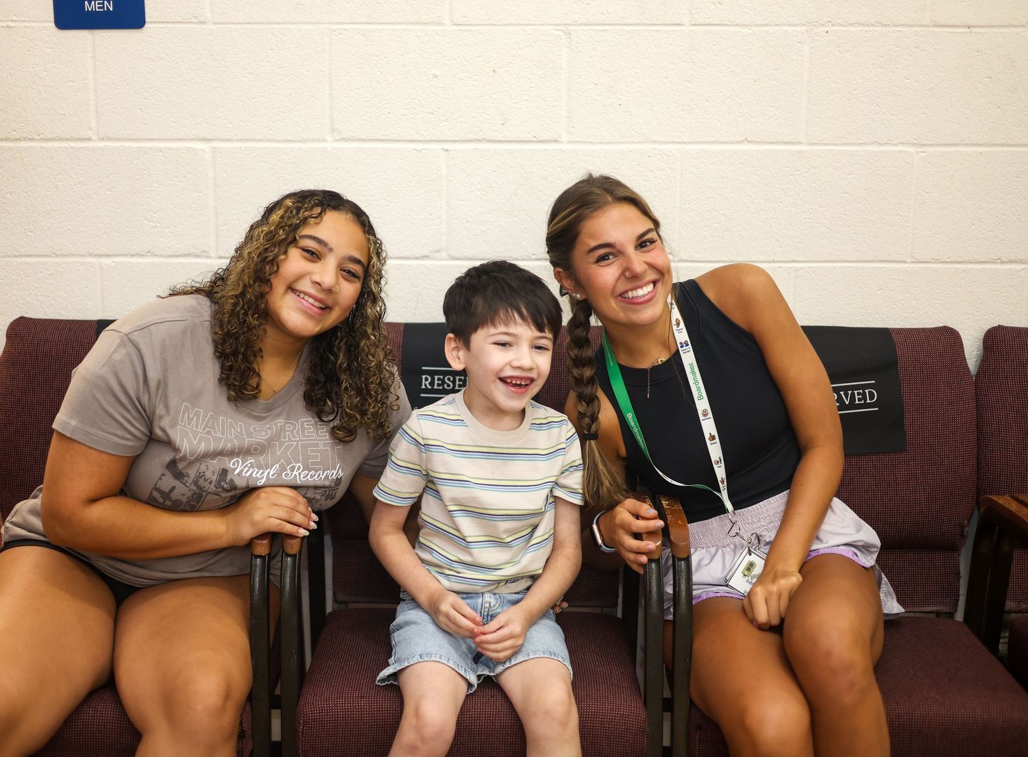 Three cheerful people sitting together on a couch smiling and enjoying each other's company.