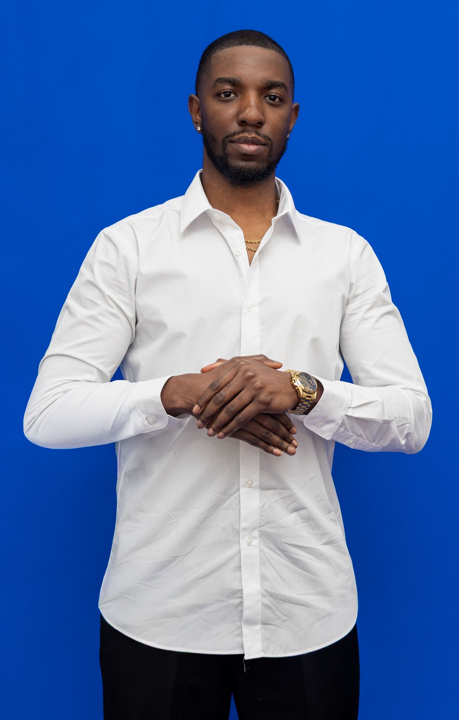 Professional studio portrait of someone wearing a crisp white button-down shirt against a vibrant blue background.