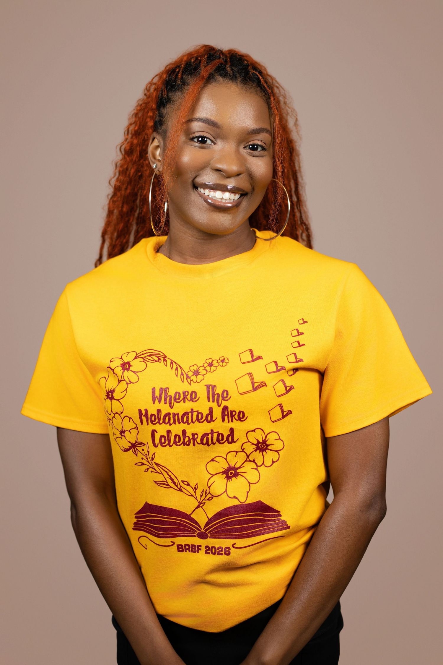 Smiling woman wearing a yellow BRBF 2023 t-shirt reading Where The Melanated Are Celebrated with floral book design.