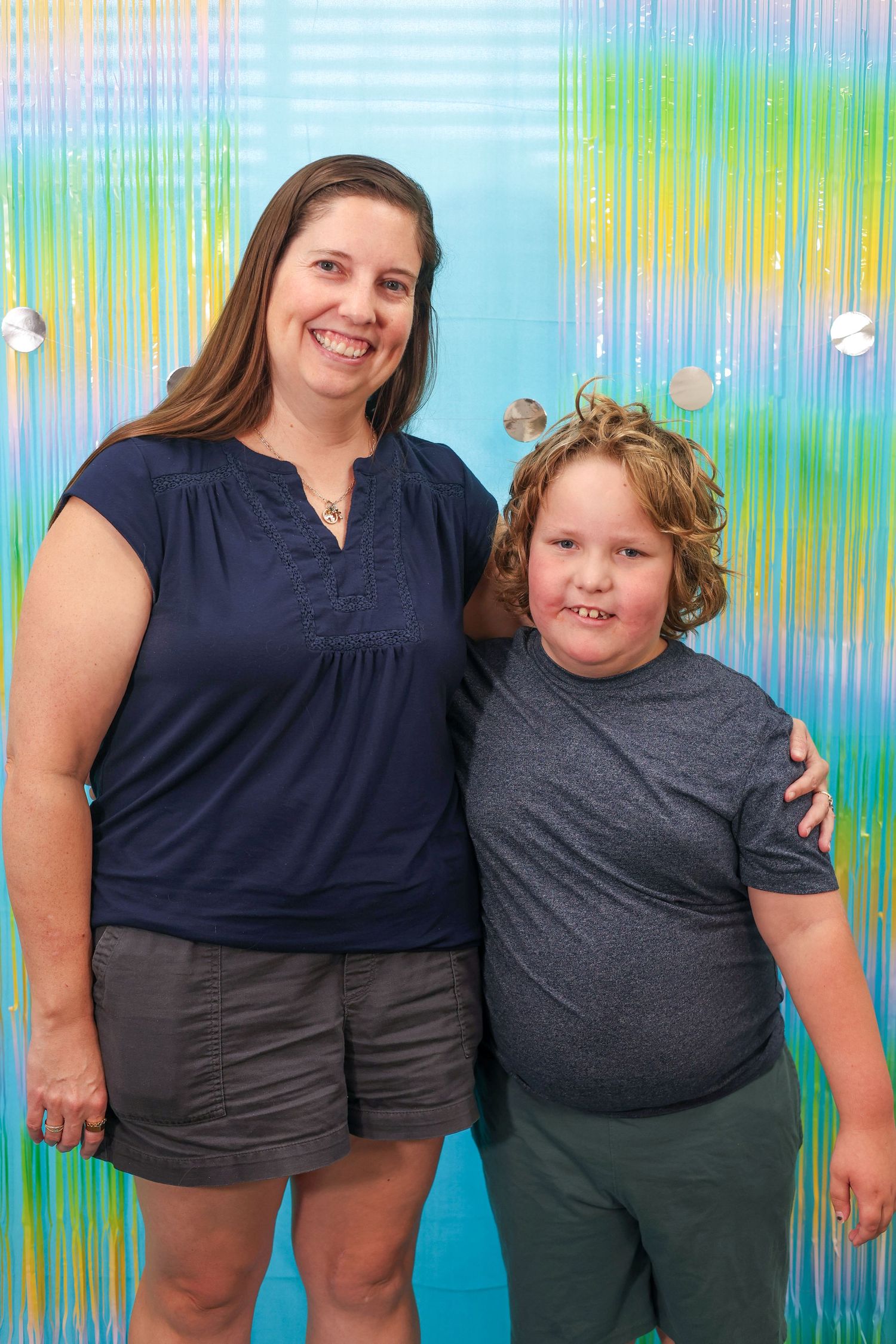 Row of people wearing dark shirts posed against a colorful streaked background.