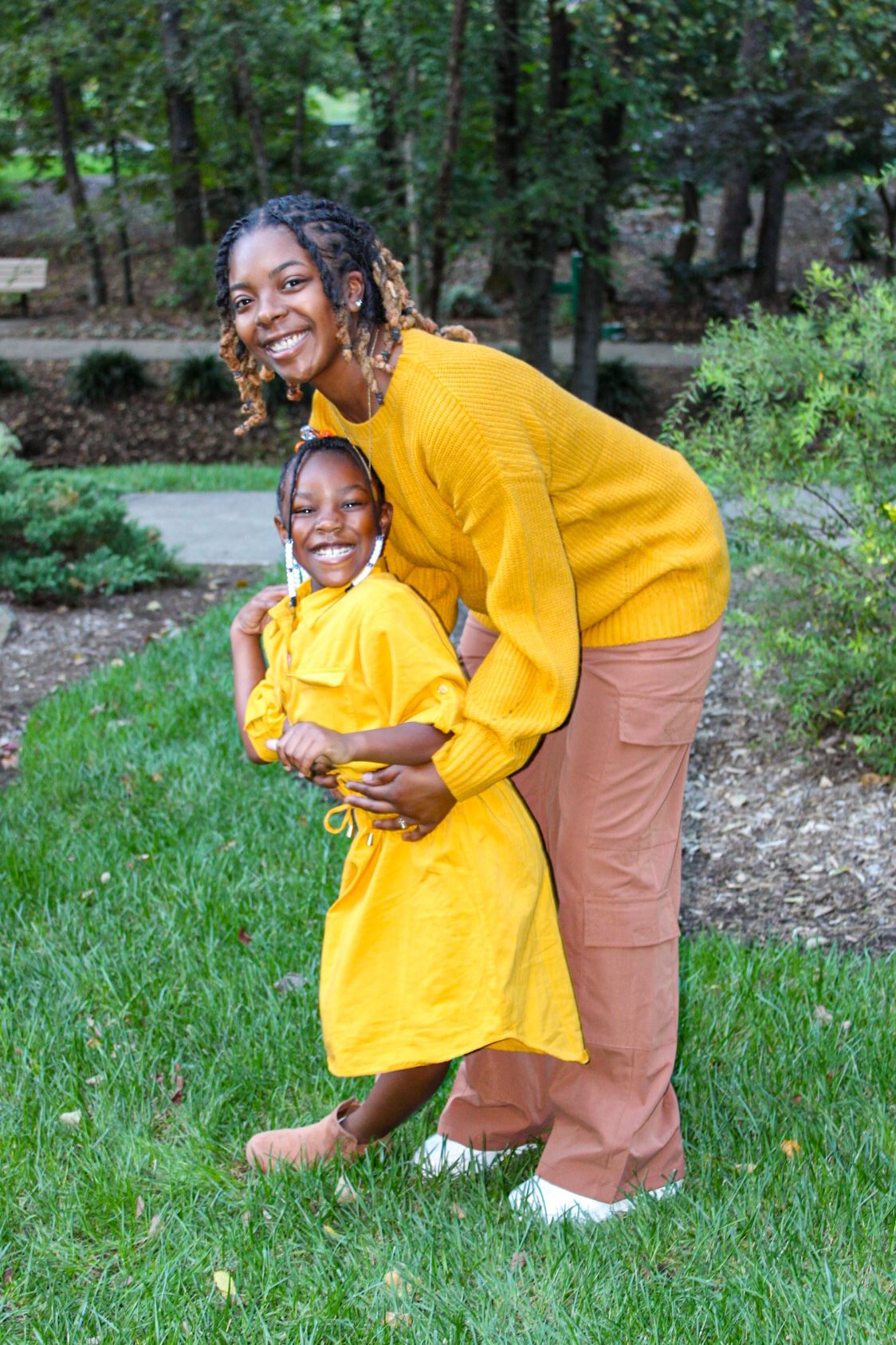 Parent and child in bright yellow and tan outfits playing together on green grass.
