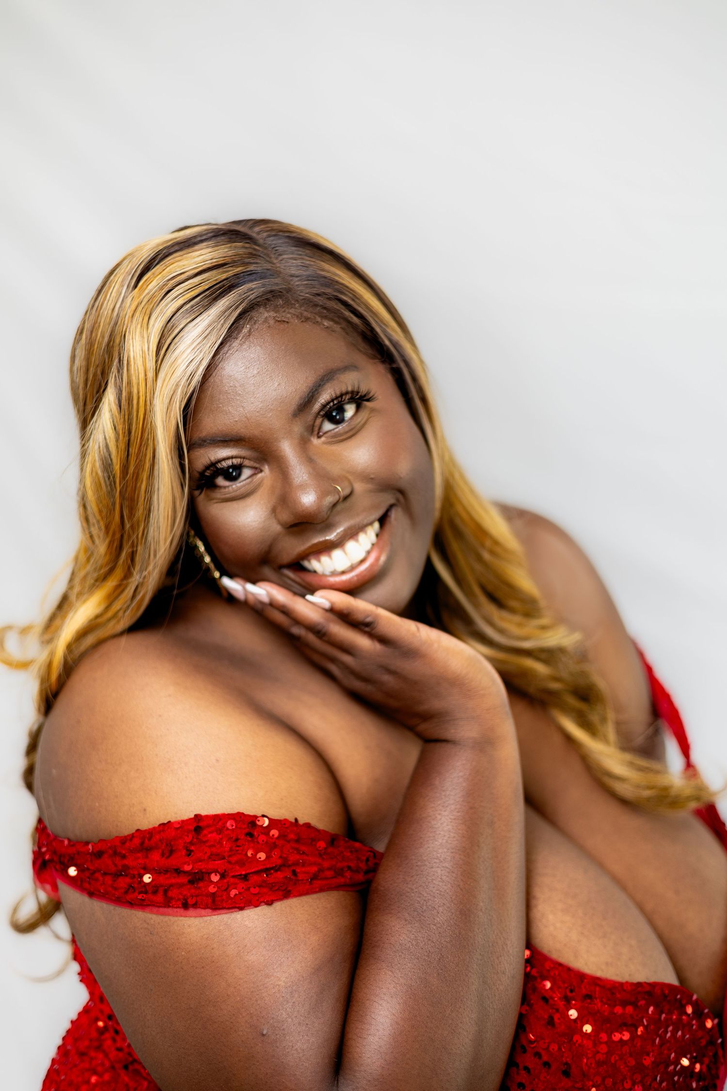 A person in a sparkly red off-shoulder dress poses against a light background.