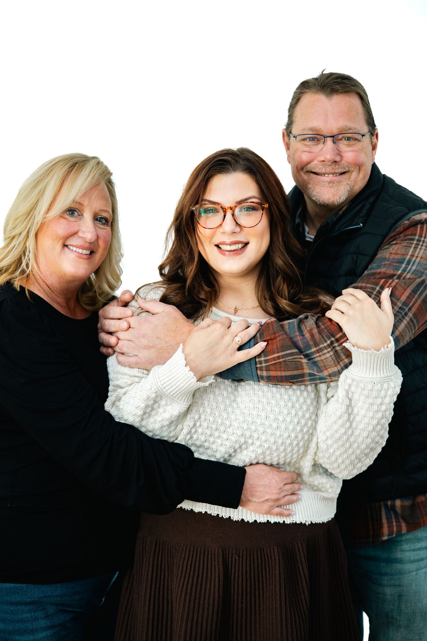 A family wearing coordinated outfits in brown and white poses together for a series of casual portrait photos.