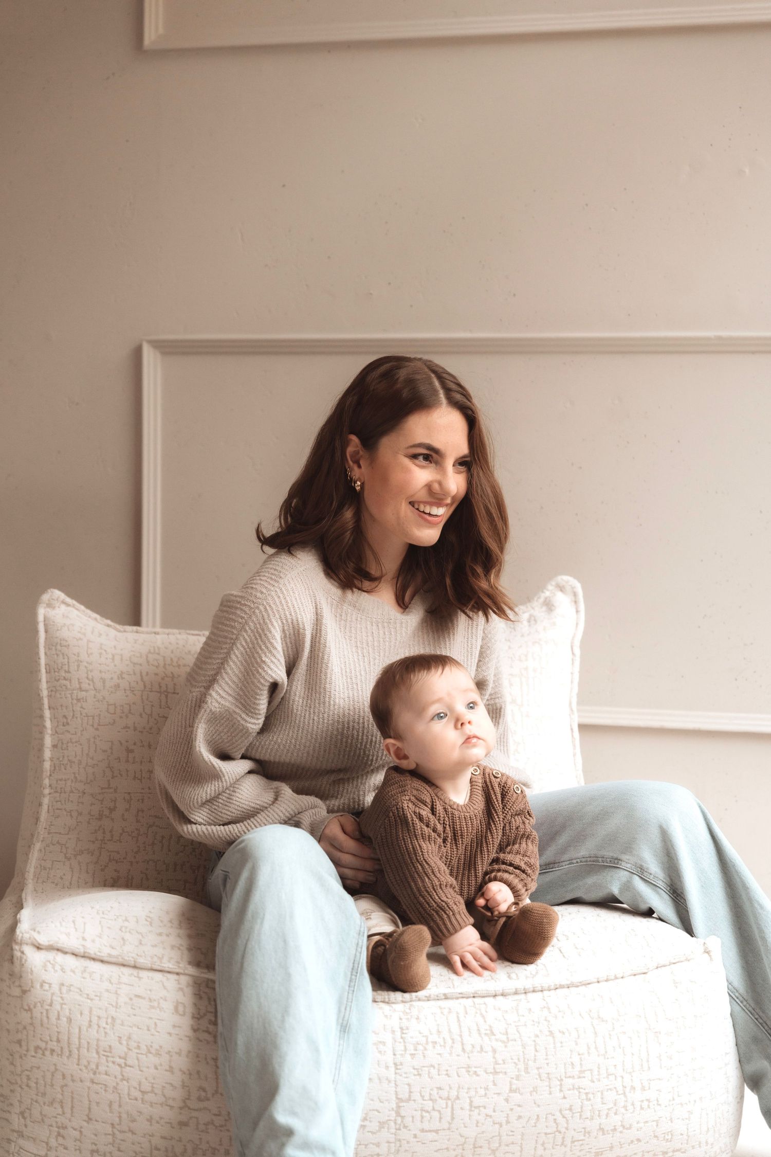 Parent and baby sharing tender moment on white couch with blue accents.