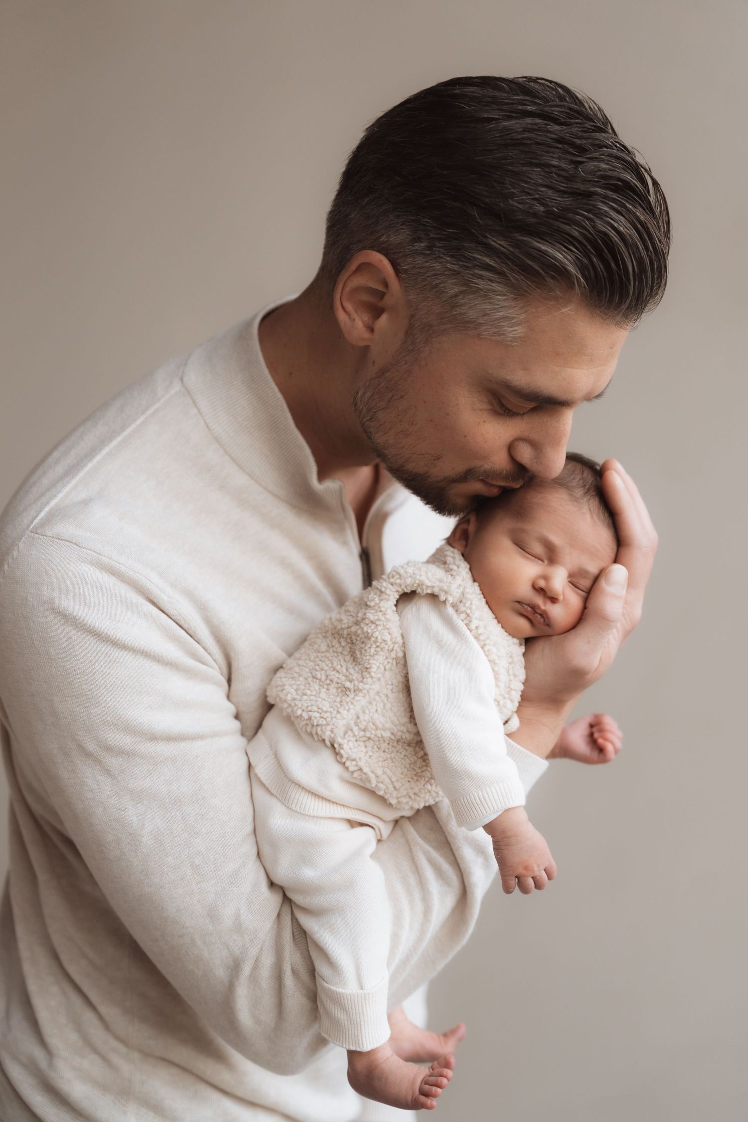 A tender moment captured in a series of black and white photos showing a parent cradling and kissing a newborn baby.