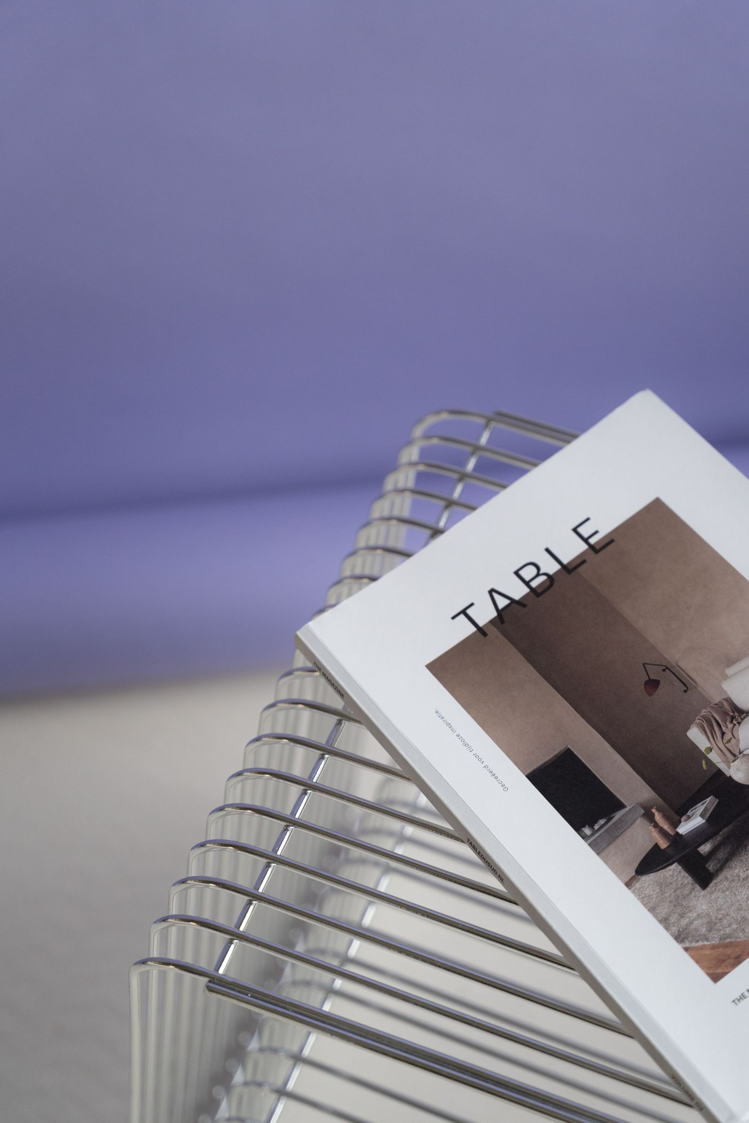 A book titled 'Table' rests on a spiral metal wire structure against a purple background.