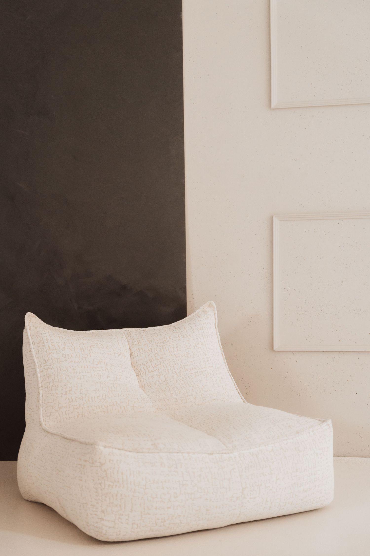 White textured lounge chair shown from multiple angles against a dark wall with minimalist styling.